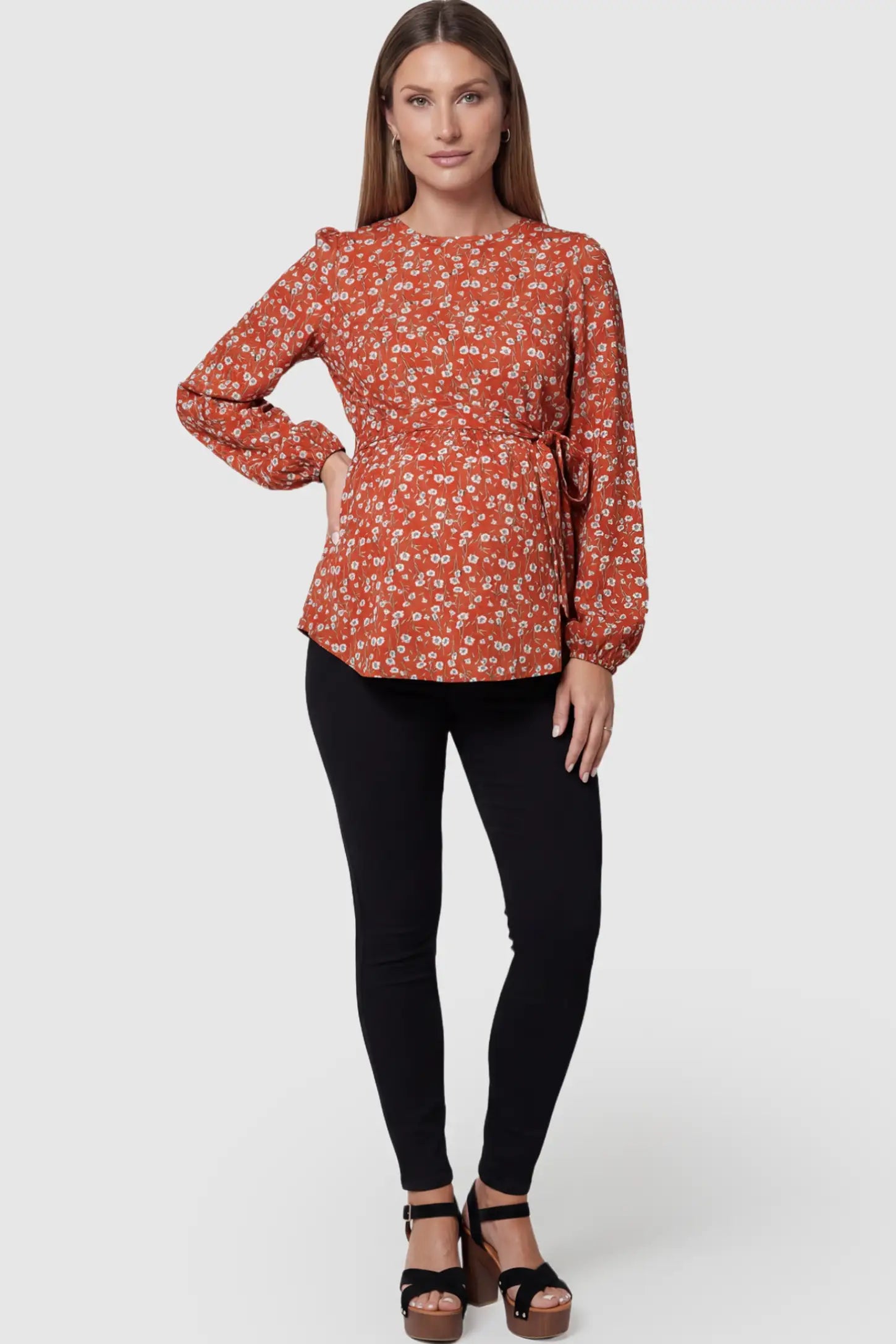 Floral Round Neck Babydoll Maternity Top Floral Round Neck Babydoll Maternity Top in Red featuring an adjustable waist tie on a pregnant model posing front.