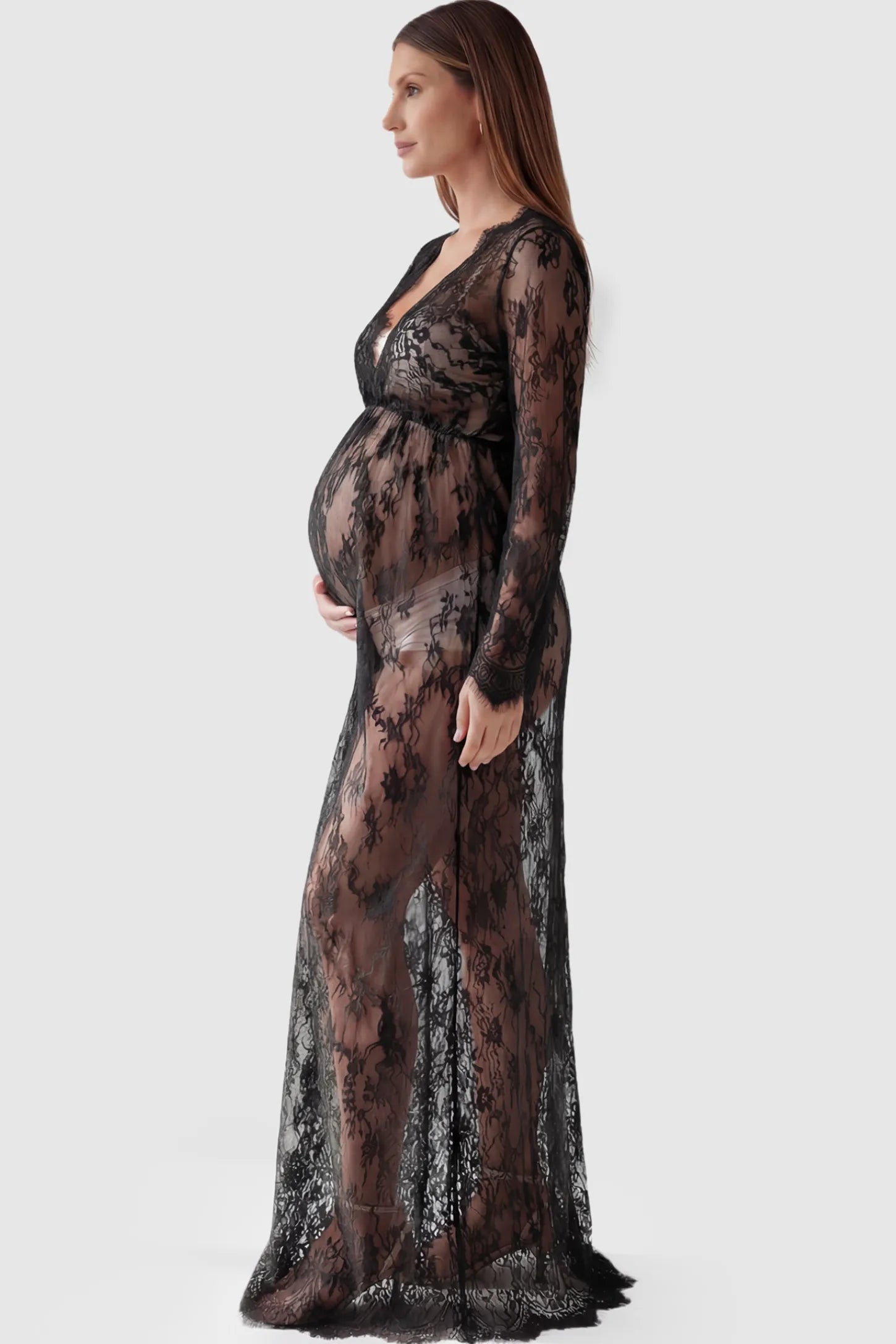 Floral Sheer Lace Long Sleeve Maternity Photoshoot Gown Floral Sheer Lace Maternity Gown in Black featuring scalloped v-neck and long sleeves on a pregnant model showing side.