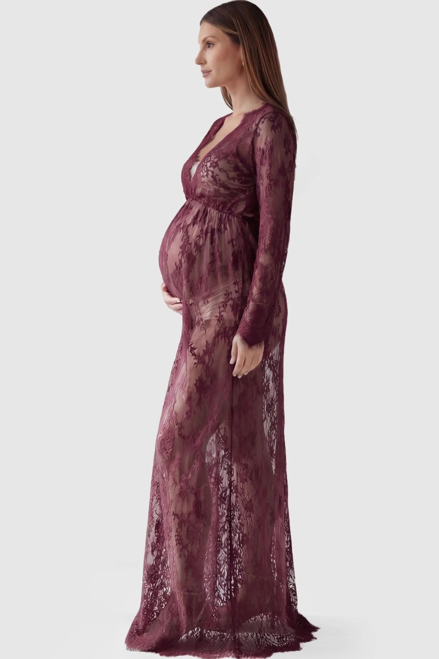 Floral Sheer Lace Long Sleeve Maternity Photoshoot Gown Floral Sheer Lace Maternity Gown in Burgundy featuring scalloped v-neck and long sleeves on a pregnant model showing side.