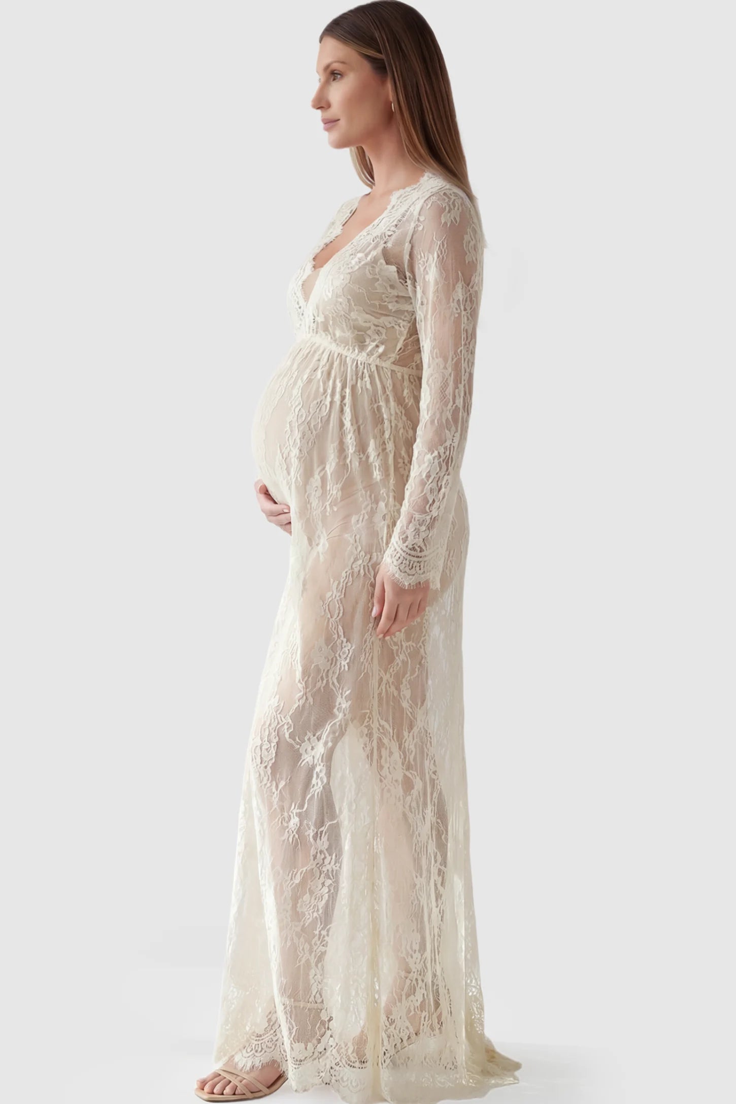 Floral Sheer Lace Long Sleeve Maternity Photoshoot Gown Floral Sheer Lace Maternity Gown in Ivory featuring scalloped v-neck and long sleeves on a pregnant model showing side.