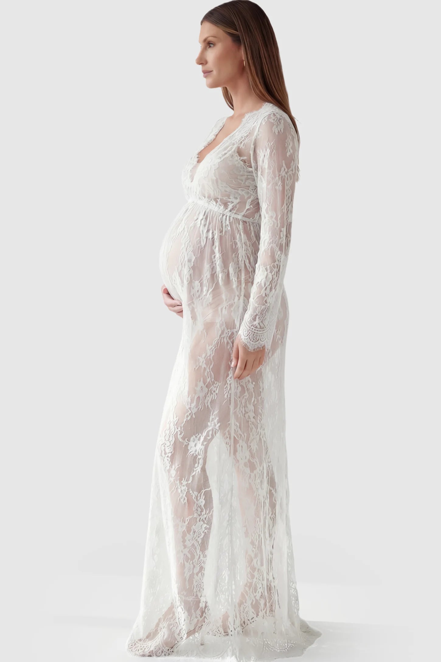 Floral Sheer Lace Long Sleeve Maternity Photoshoot Gown Floral Sheer Lace Maternity Gown in White featuring scalloped v-neck and long sleeves on a pregnant model showing side.