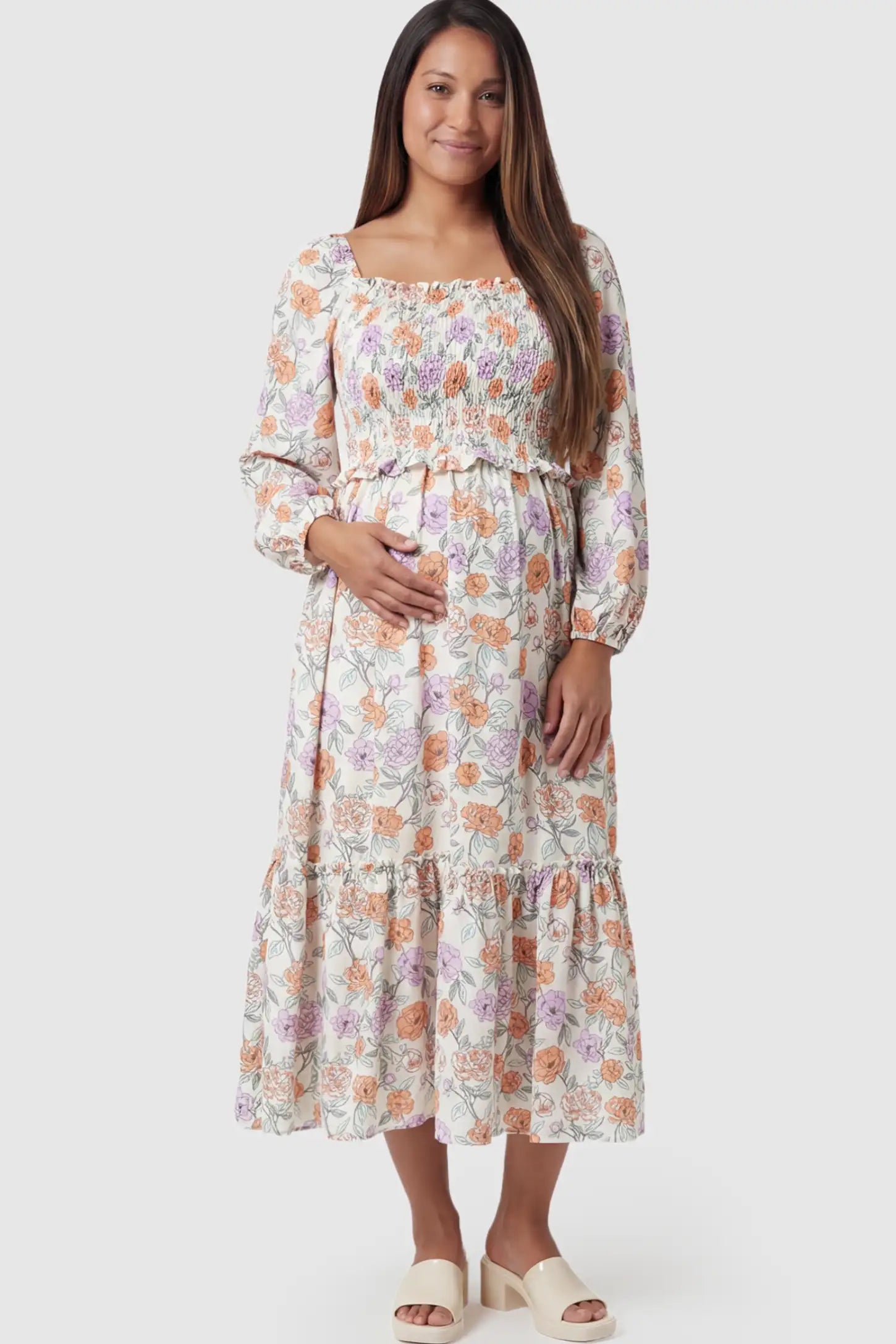 Floral Smocked Bodice Tiered Maternity Midi Dress Floral Smocked Bodice Tiered Midi Dress in floral print featuring a smocked square neckline on a pregnant model showing front.