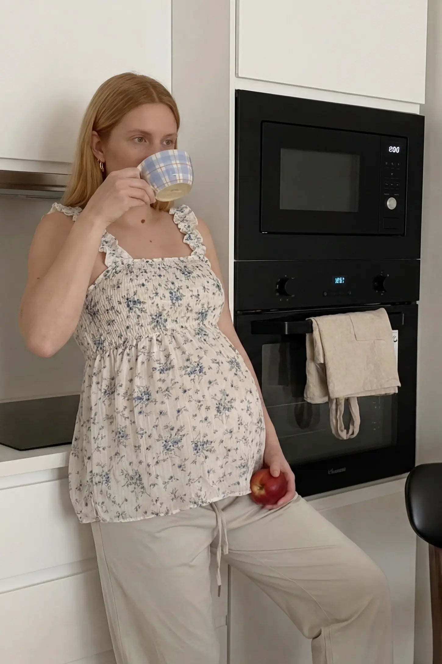 Floral Square Neck Babydoll Maternity Top Floral Square Neck Babydoll Maternity Top in Beige featuring a smocked bodice and flowy hem on a pregnant model, lifestyle view.