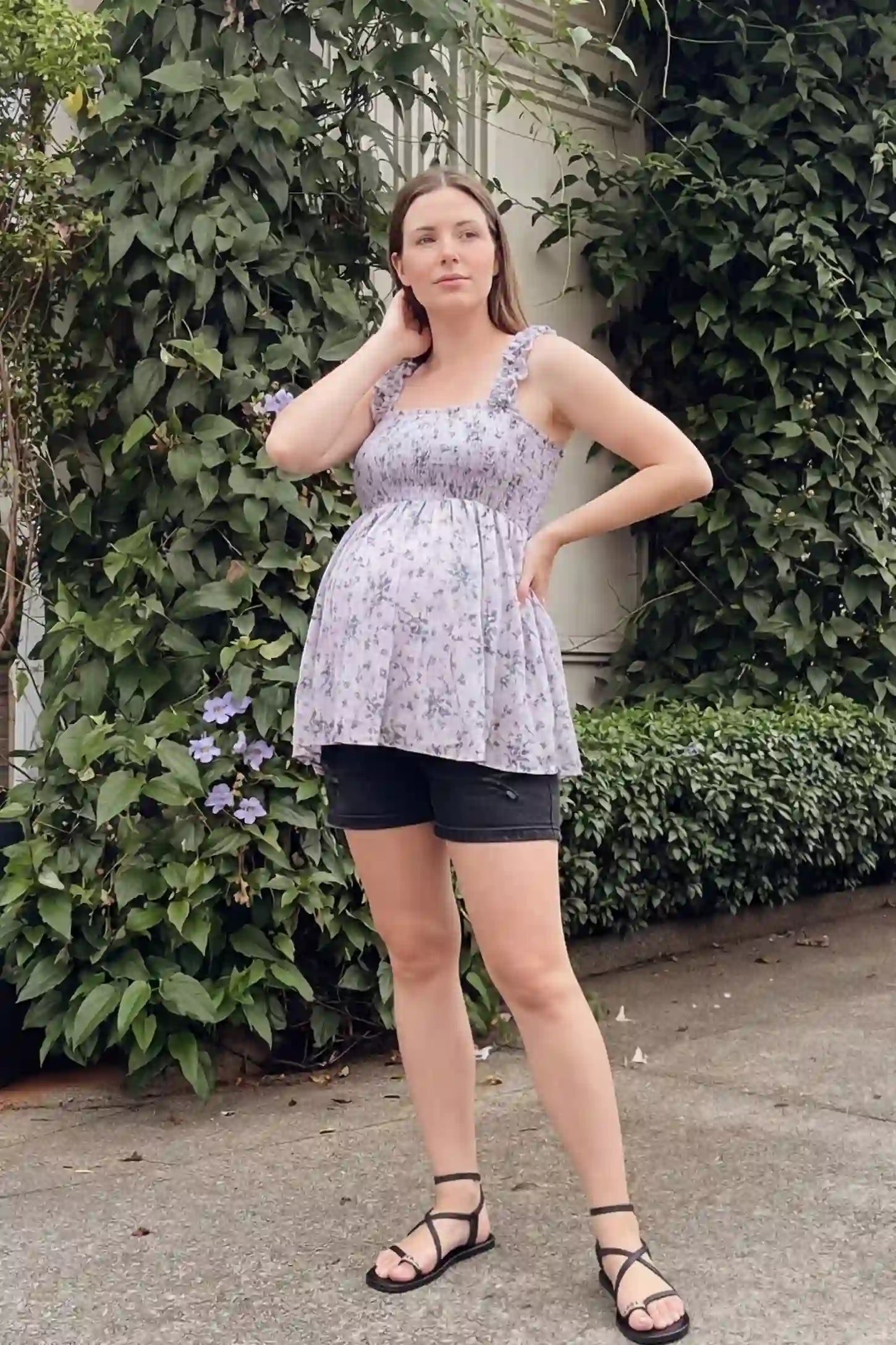 Floral Square Neck Babydoll Maternity Top Floral Square Neck Babydoll Maternity Top in Purple featuring a smocked bodice and flowy babydoll hem on a pregnant model, lifestyle UGC view.
