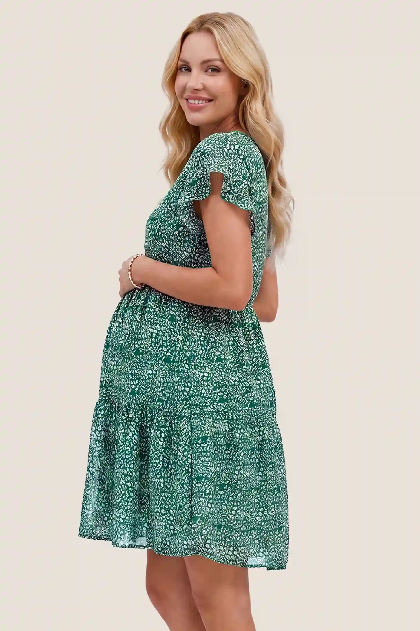 Floral V-Neck A-Line Flutter Sleeve Short Maternity Dress Floral V-Neck A-Line Flutter Sleeve Short Maternity Dress in Green with an accommodating A-line silhouette, side view on a pregnant model.