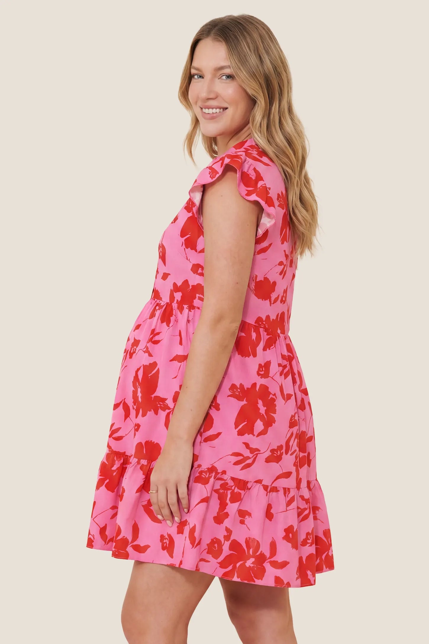Floral Print V-Neck Flutter Sleeve Maternity Short Dress Floral Print V-Neck Flutter Sleeve Maternity Short Dress in Red showing the A-line flow over the belly, side view on a pregnant model.