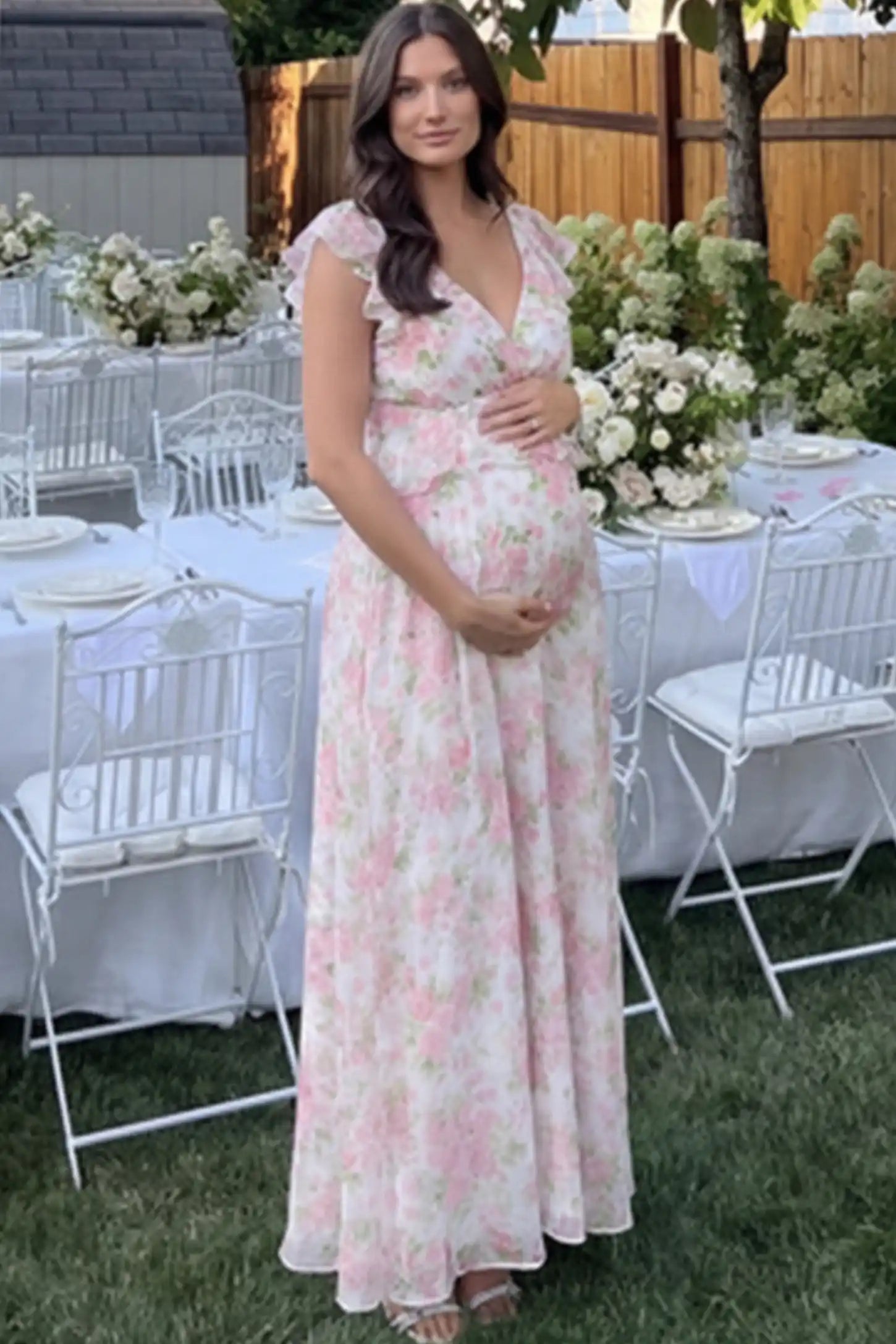 Floral V-Neck Ruffle Backless Maternity Maxi Dress Floral Print V-Neck Ruffle Backless Maxi Maternity Dress with a peplum waist and flutter sleeves on a pregnant woman.