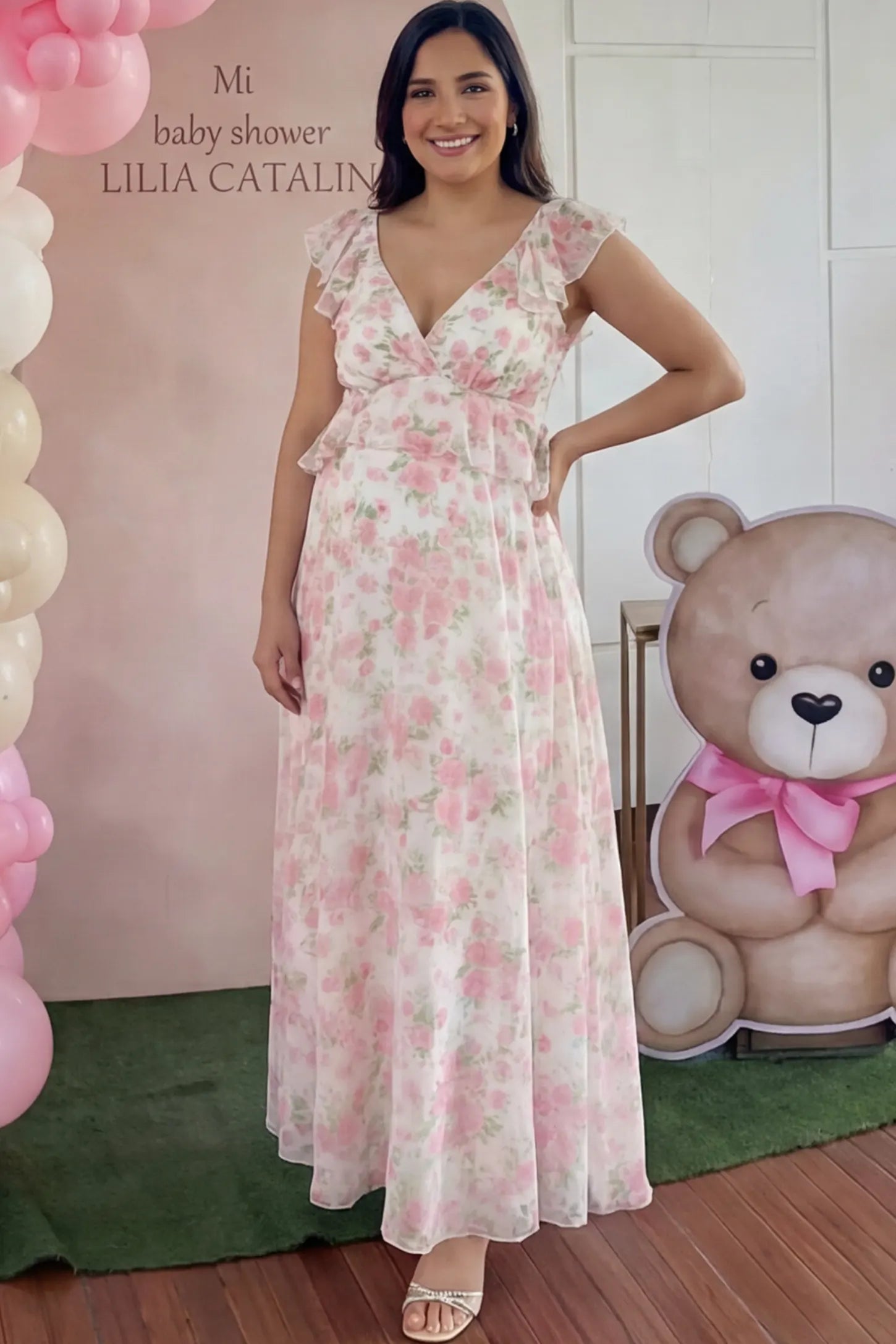 Floral Print V-Neck Ruffle Backless Maxi Maternity Dress with a peplum waist and flutter sleeves on a pregnant woman showing front.