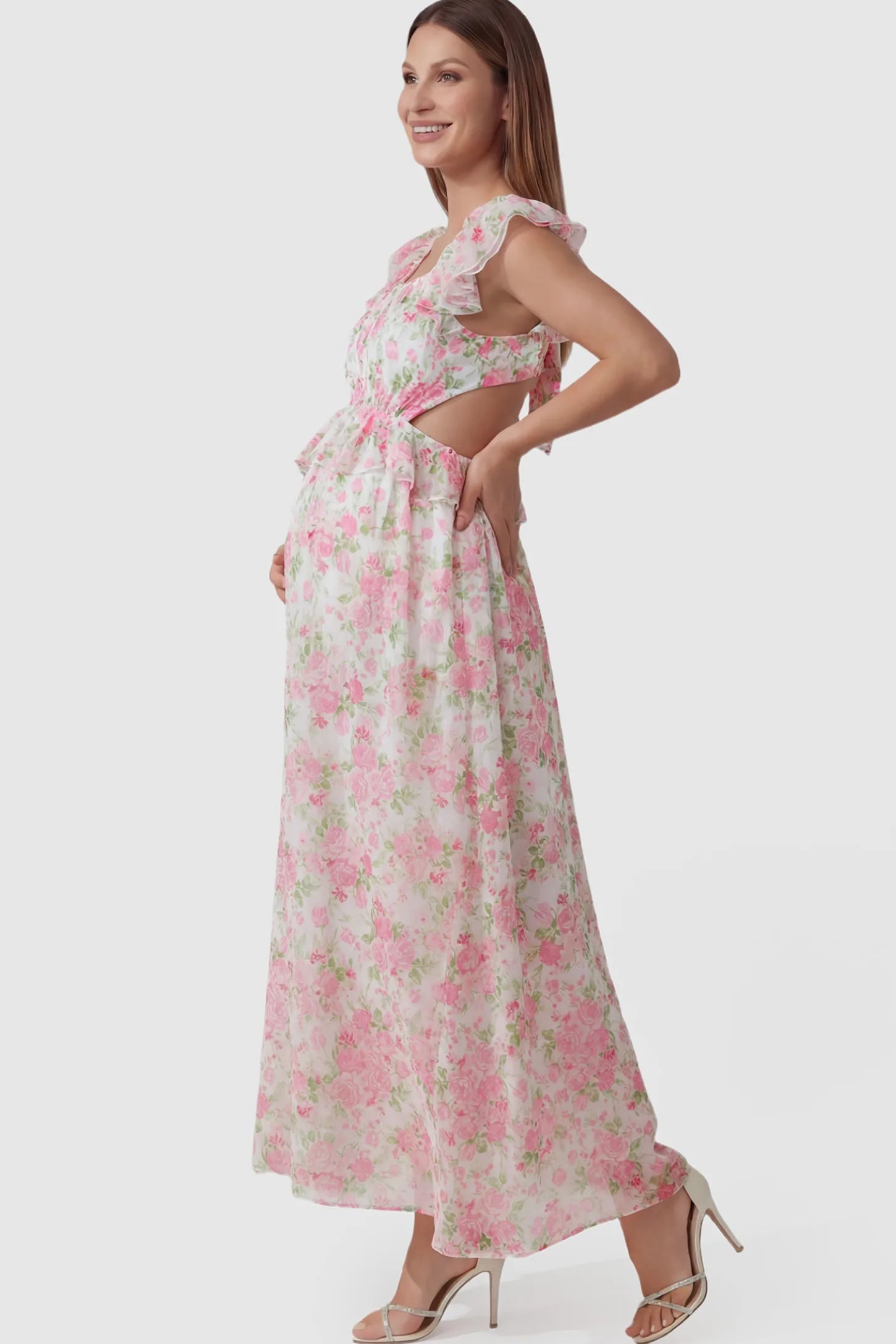 Floral V-Neck Ruffle Backless Maternity Maxi Dress Floral Print V-Neck Ruffle Backless Maxi Maternity Dress with a peplum waist and flutter sleeves on a pregnant model showing side.