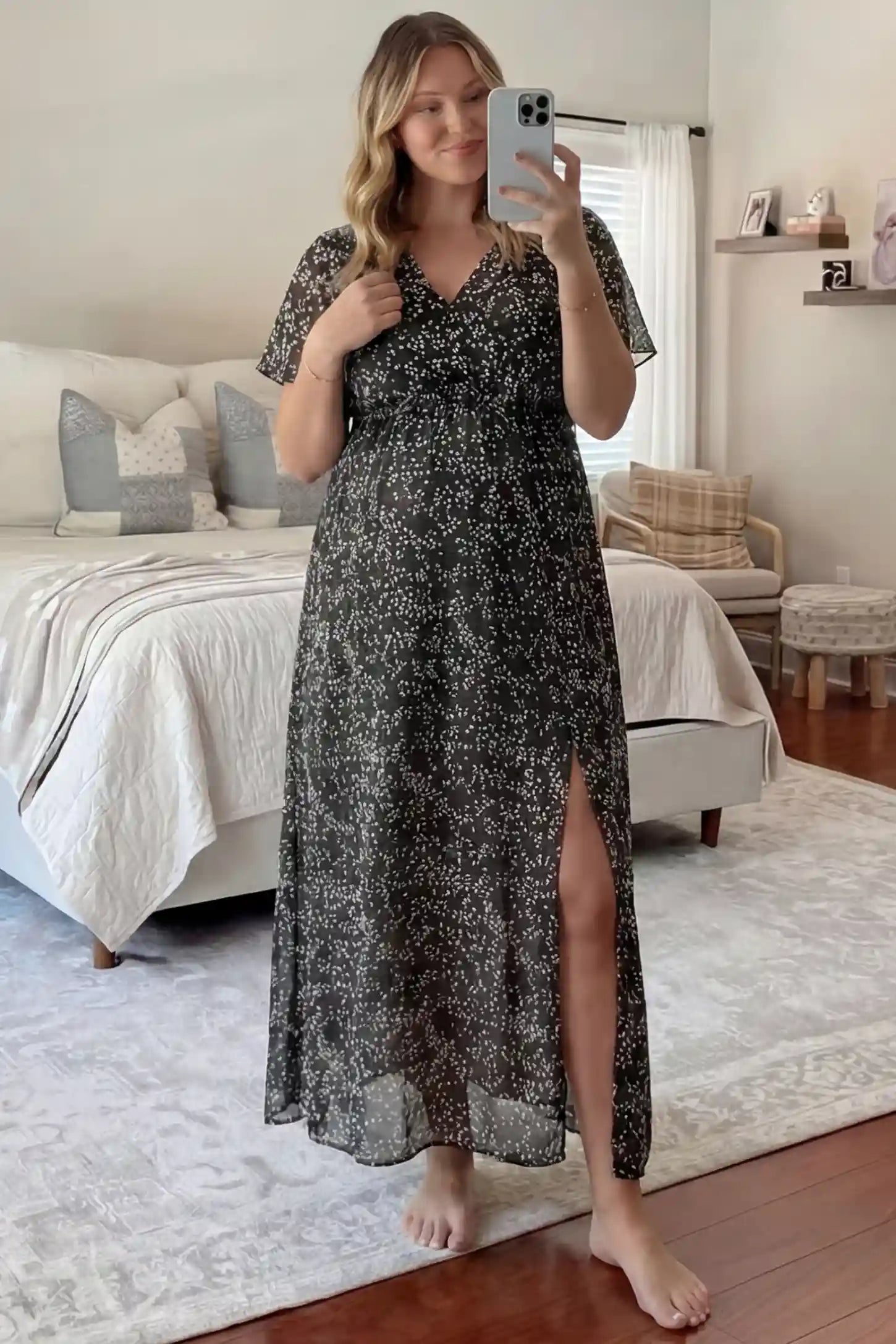 Floral V-Neck Side-Slit Maternity Maxi Dress Floral V-Neck Side-Slit Maternity Maxi Dress in black featuring short sleeves and a side leg slit, shown on a pregnant woman taking a mirror selfie in a bedroom, front view.