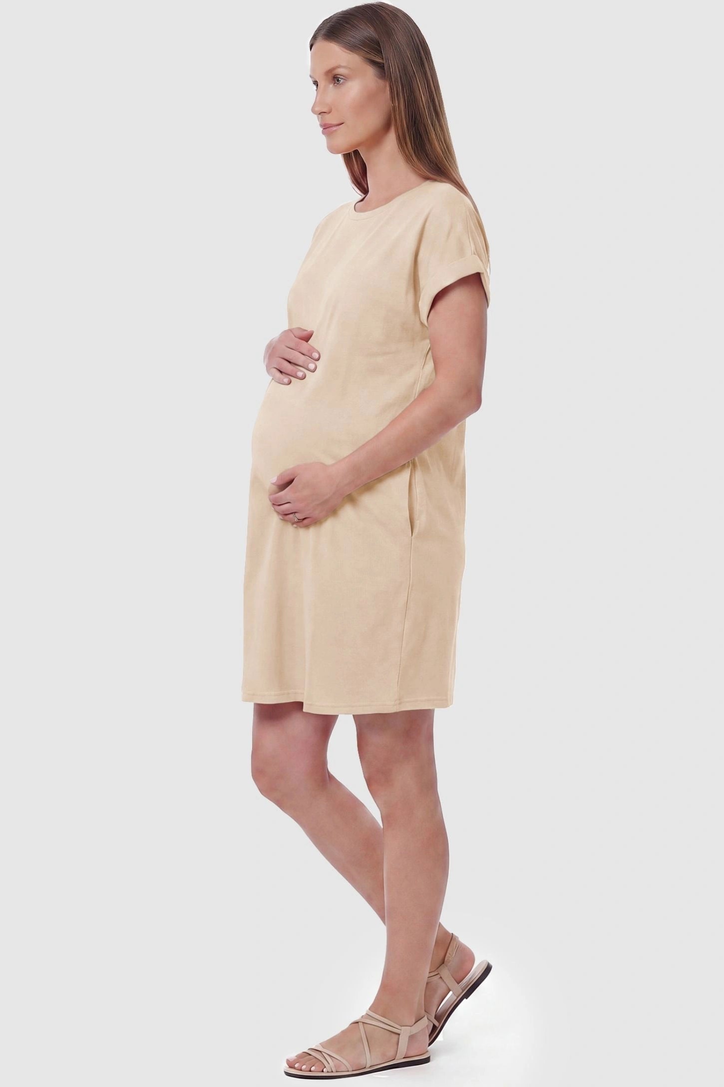 Flowy Pocket Tunic Maternity T-Shirt Dress Flowy Pocket Tunic Maternity T-Shirt Dress in Beige featuring functional side pockets on a side-view pregnant model.