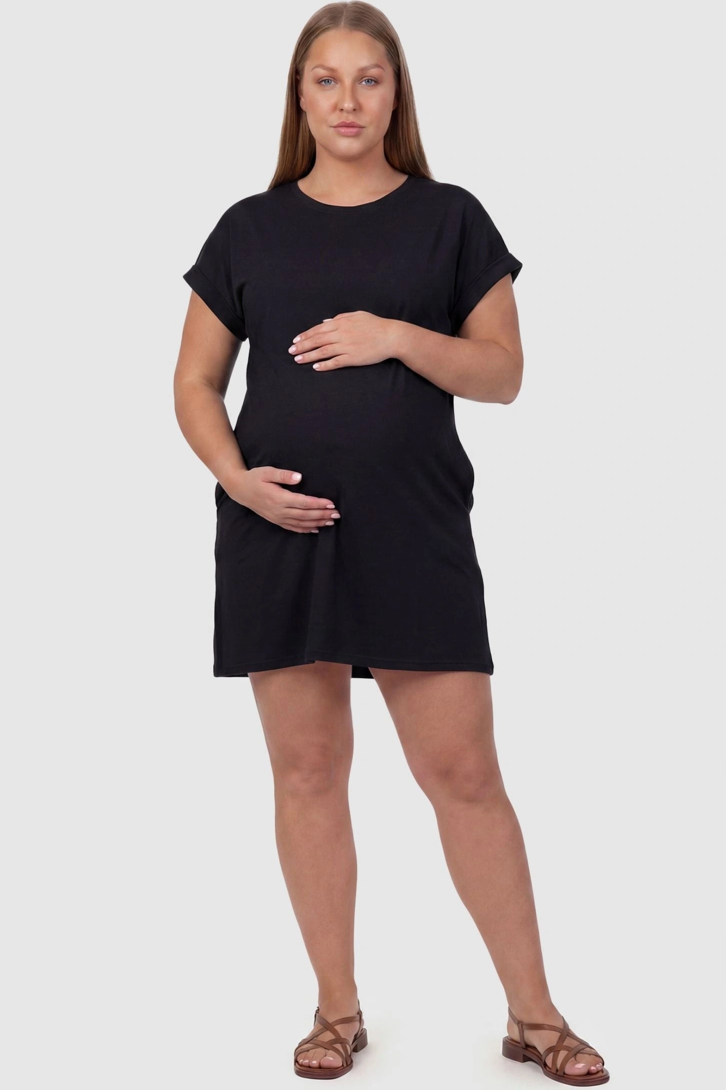 Flowy Pocket Tunic Maternity T-Shirt Dress Flowy Pocket Tunic Maternity T-Shirt Dress in Black featuring cuffed short sleeves on a front-view plus size model.