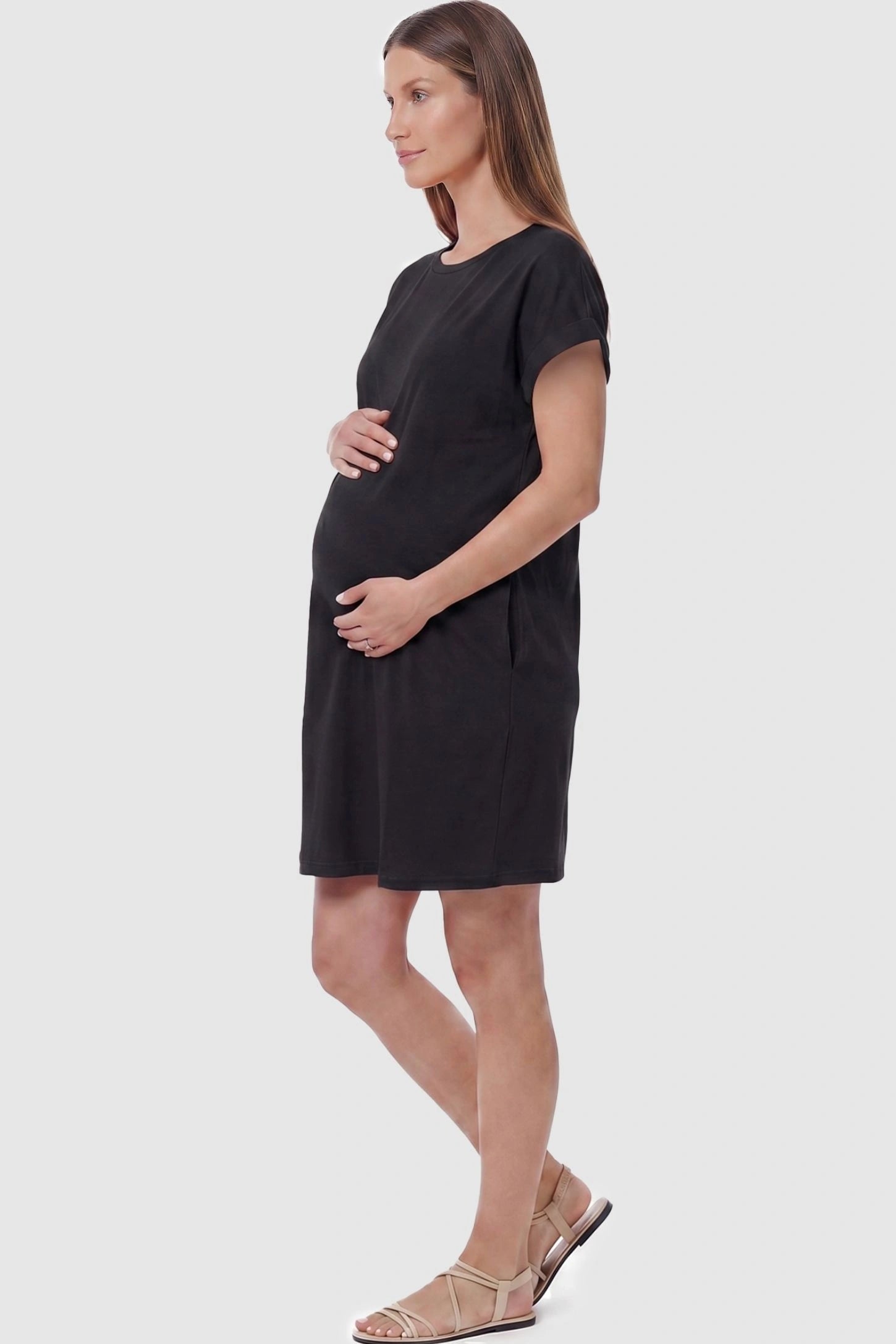 Flowy Pocket Tunic Maternity T-Shirt Dress Flowy Pocket Tunic Maternity T-Shirt Dress in Black featuring functional side pockets on a side-view pregnant model.
