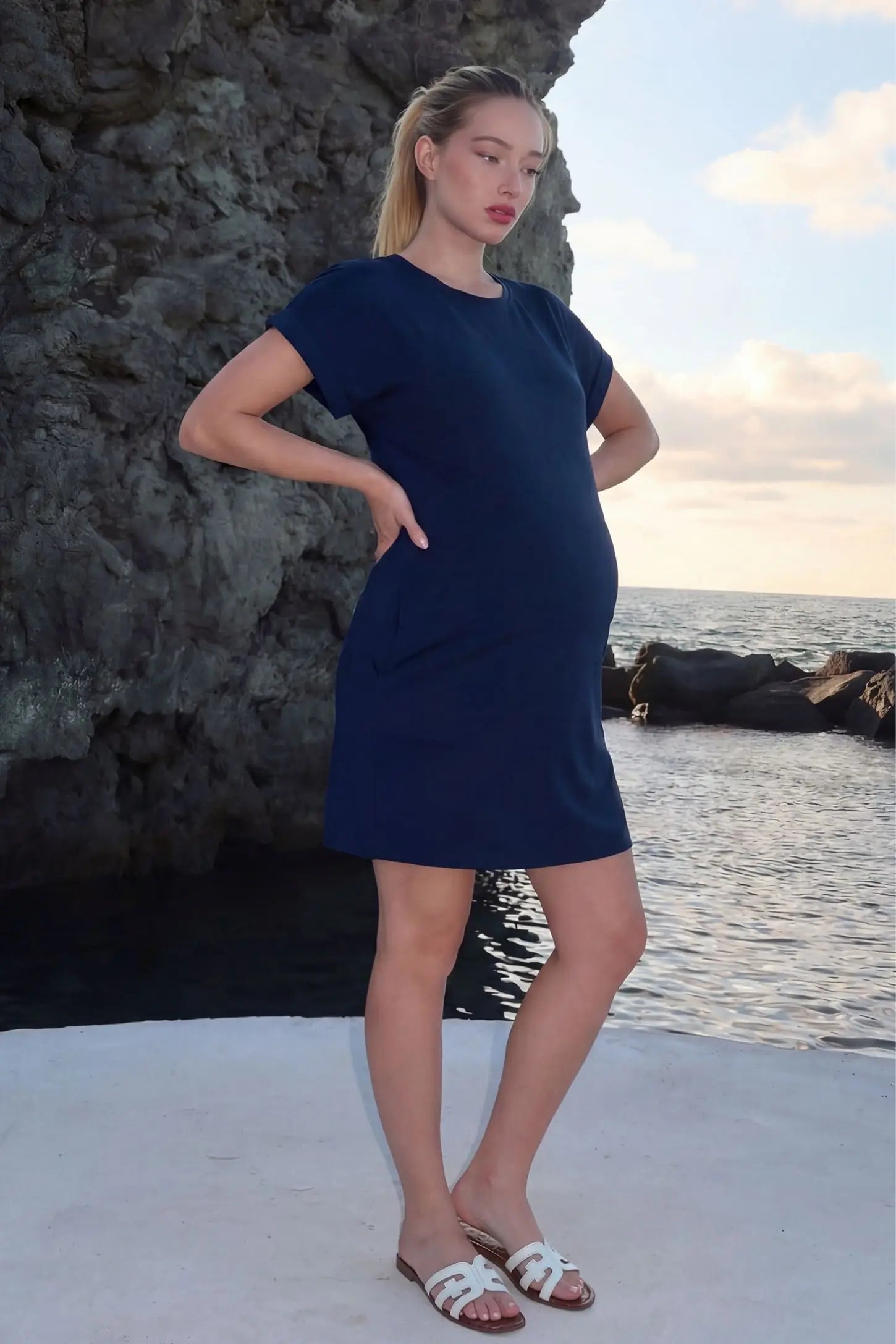 Flowy Pocket Tunic Maternity T-Shirt Dress Flowy Pocket Tunic Maternity T-Shirt Dress in Navy Blue featuring functional side pockets on a side-view pregnant model.
