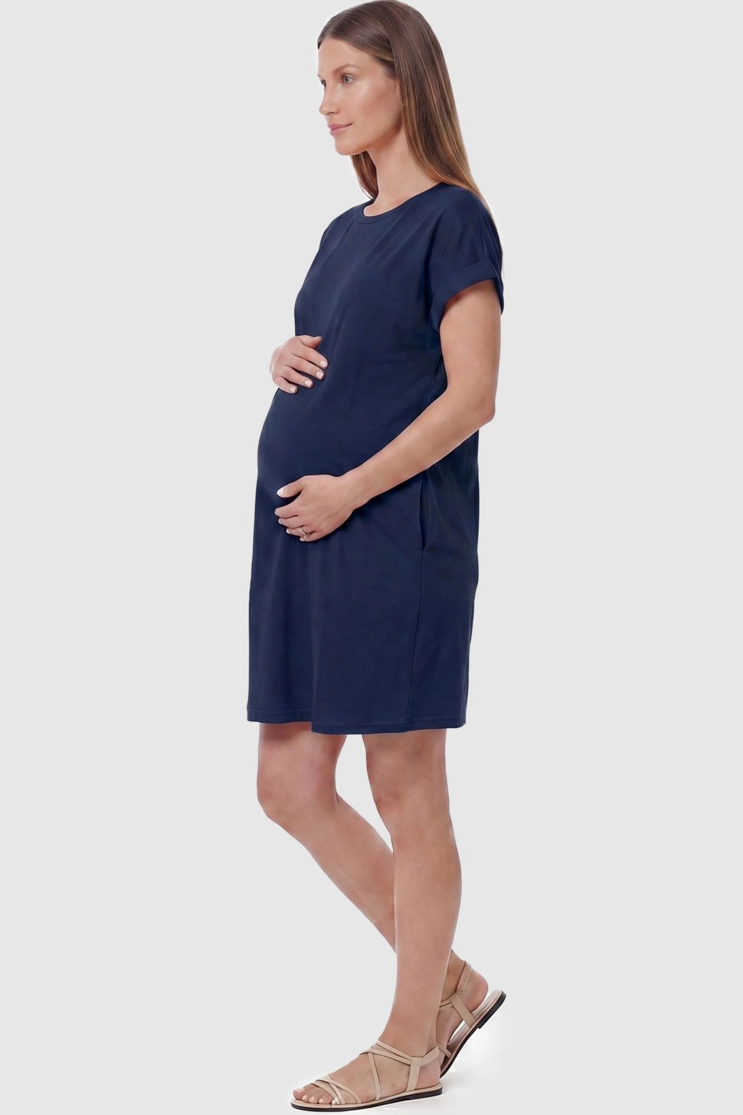 Flowy Pocket Tunic Maternity T-Shirt Dress Flowy Pocket Tunic Maternity T-Shirt Dress in Navy Blue featuring functional side pockets on a side-view pregnant model.