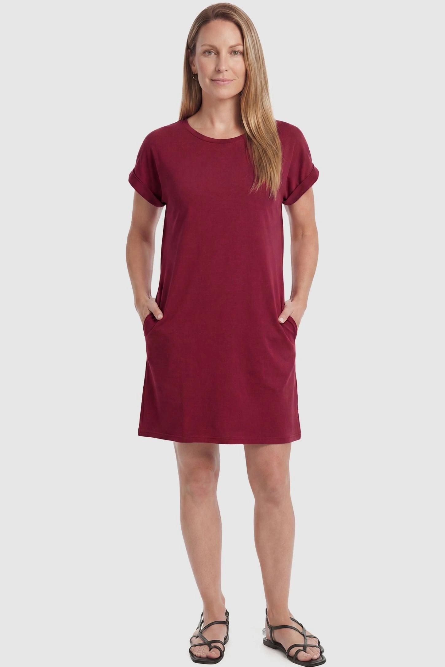 Flowy Pocket Tunic Maternity T-Shirt Dress Flowy Pocket Tunic Maternity T-Shirt Dress in Wine Red featuring cuffed short sleeves on a front-view postpartum model.