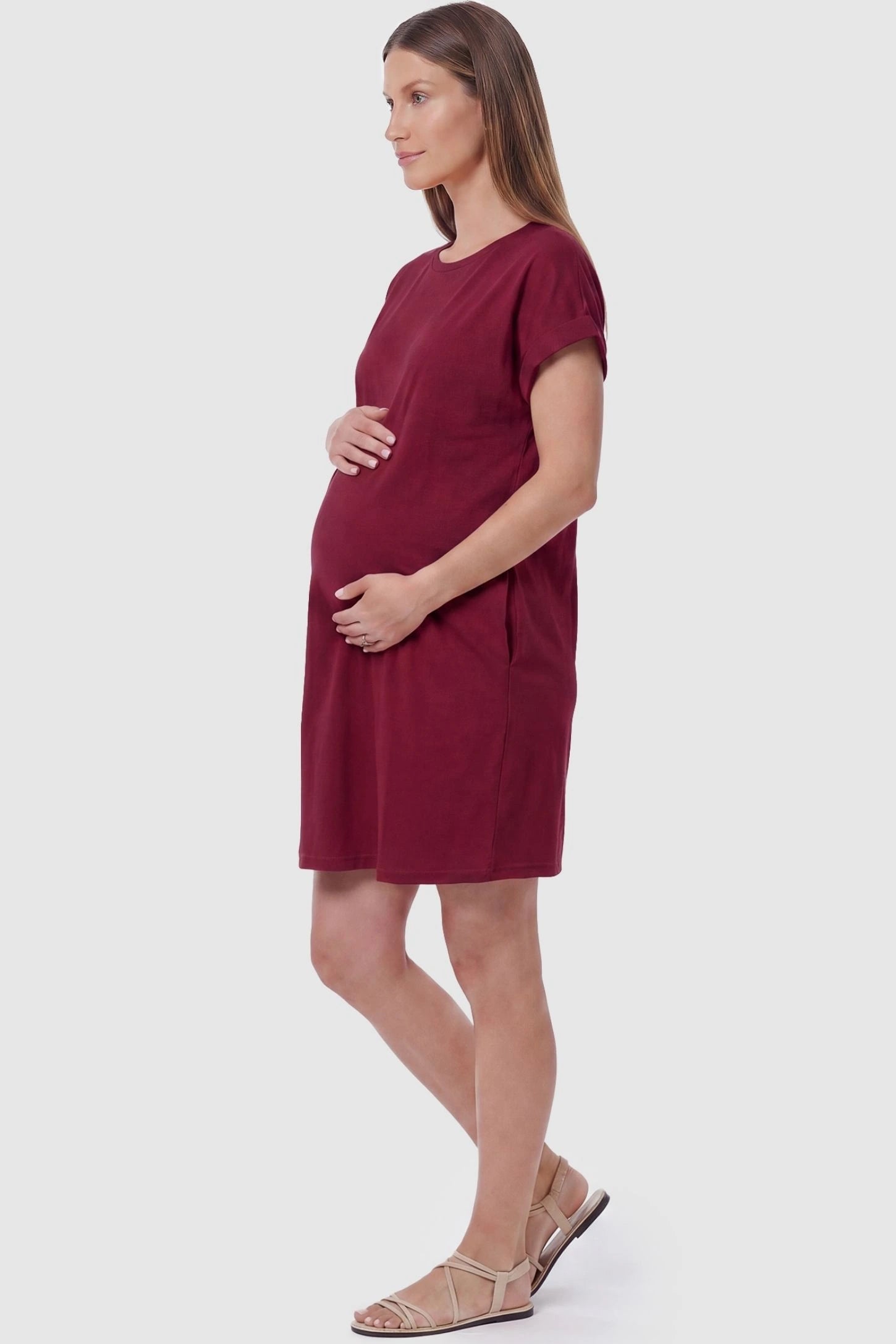 Flowy Pocket Tunic Maternity T-Shirt Dress Flowy Pocket Tunic Maternity T-Shirt Dress in Wine Red featuring functional side pockets on a side-view pregnant model.