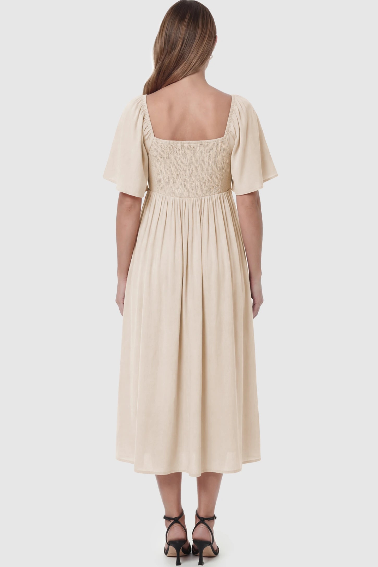 Front Tie Flutter Sleeve Maternity Midi Dress Front Tie Flutter Sleeve Maternity Midi Dress in Apricot featuring a knotted V-neckline and flowy skirt on a pregnant model showing back.