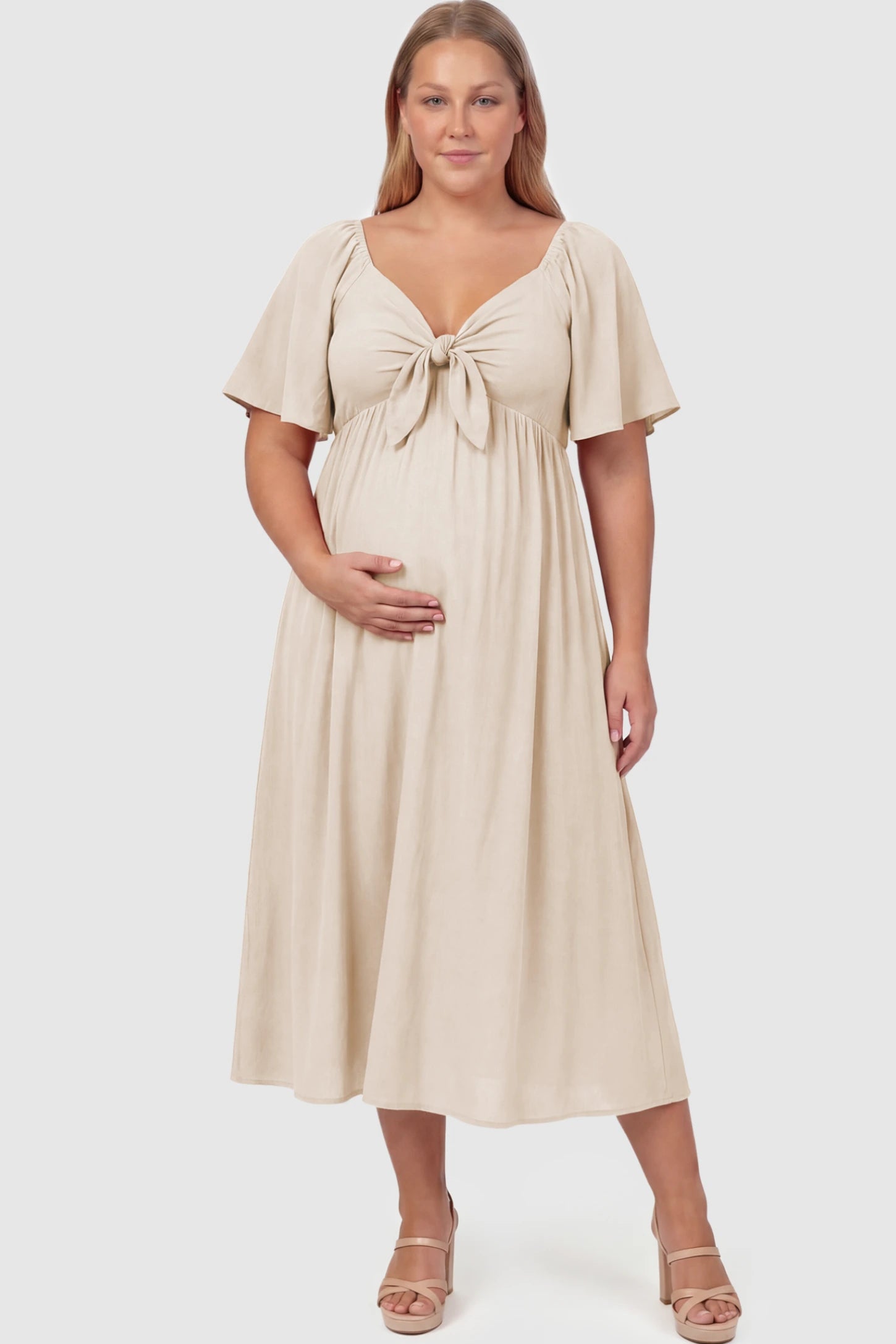 Front Tie Flutter Sleeve Maternity Midi Dress Front Tie Flutter Sleeve Maternity Midi Dress in Apricot featuring a knotted V-neckline and flowy skirt on a Plus Size model.