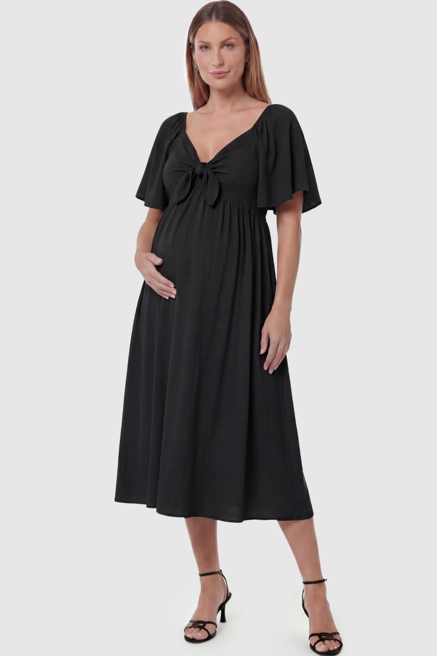 Front Tie Flutter Sleeve Maternity Midi Dress Front Tie Flutter Sleeve Maternity Midi Dress in black featuring a knotted V-neckline and flowy skirt on a pregnant model posing front.