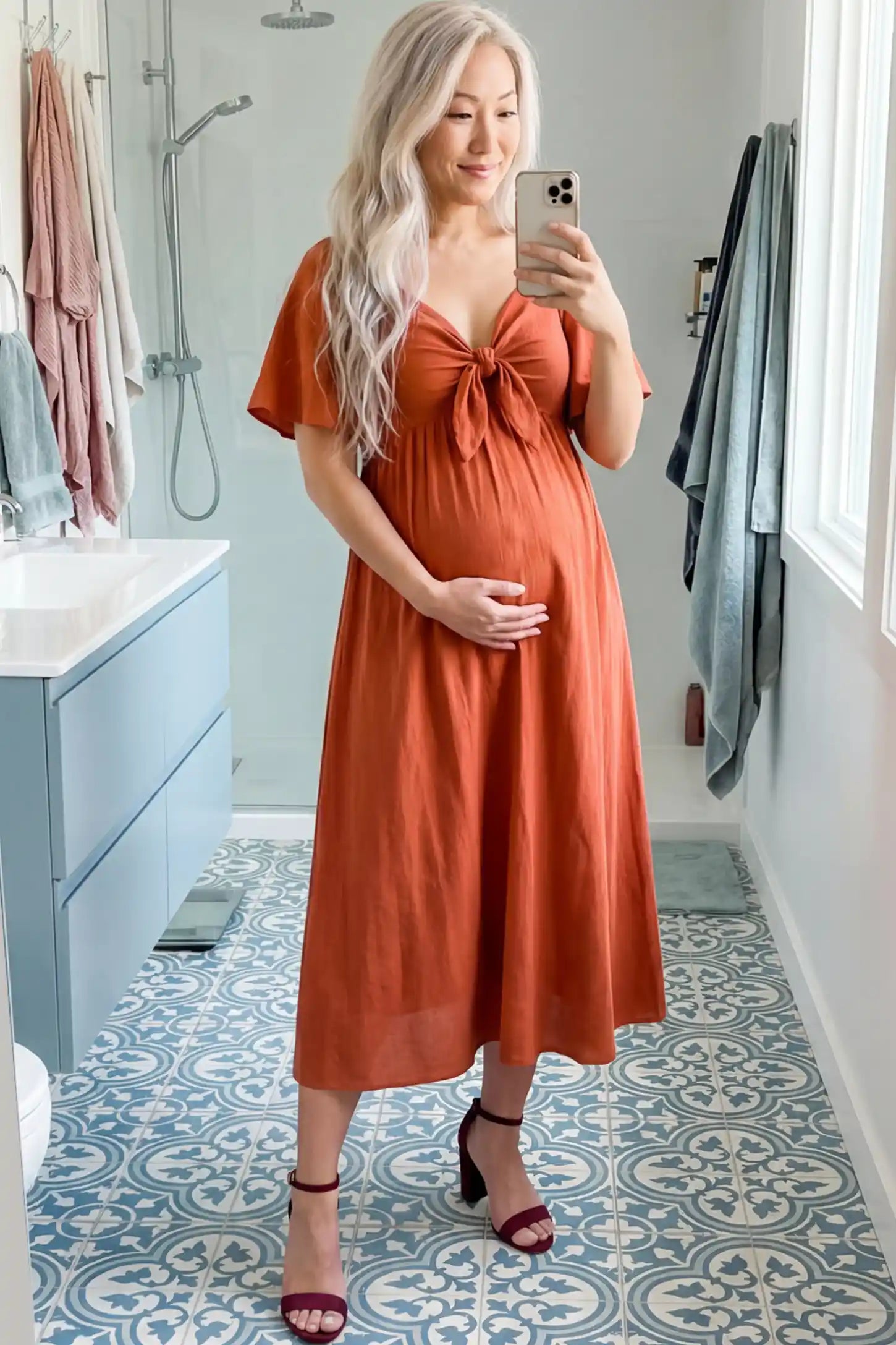 Front Tie Flutter Sleeve Maternity Midi Dress Front Tie Flutter Sleeve Maternity Midi Dress in Brick Red featuring a knotted V-neckline and flowy skirt on a pregnant woman.