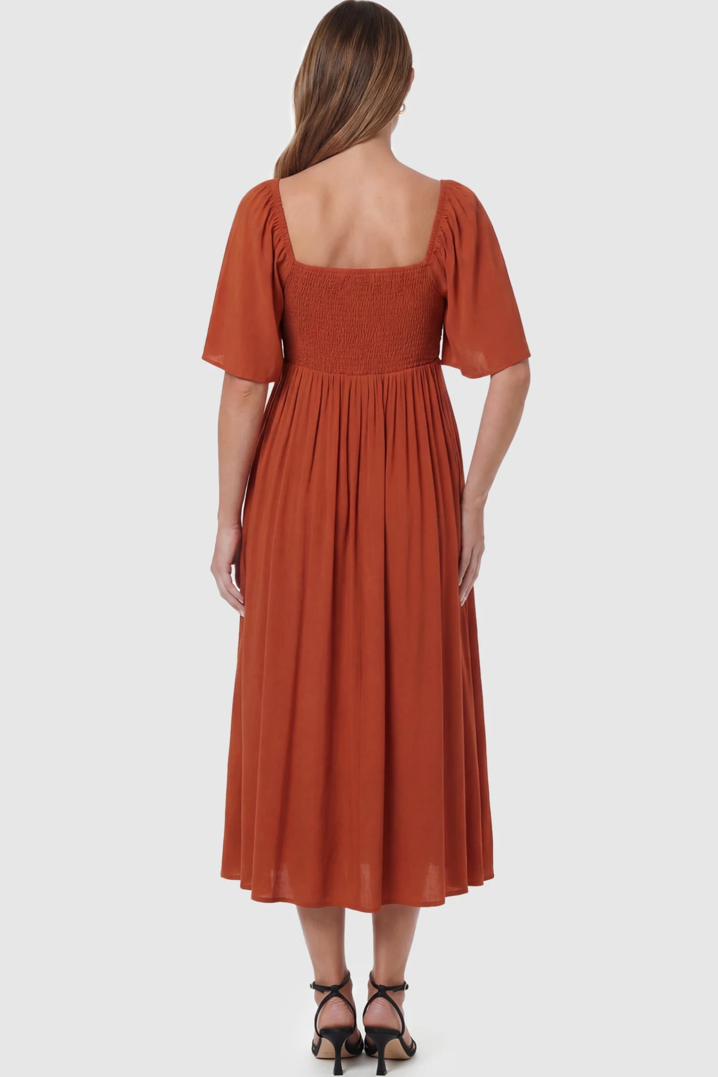 Front Tie Flutter Sleeve Maternity Midi Dress Front Tie Flutter Sleeve Maternity Midi Dress in Brick Red featuring a knotted V-neckline and flowy skirt on a pregnant model showing back.