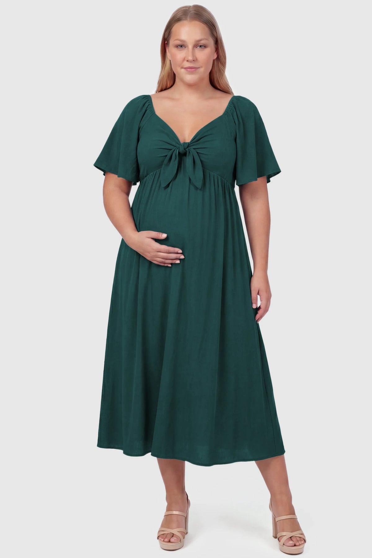 Front Tie Flutter Sleeve Maternity Midi Dress Front Tie Flutter Sleeve Maternity Midi Dress in emerald green featuring a knotted V-neckline and flowy skirt on a plus size pregnant model, front view.