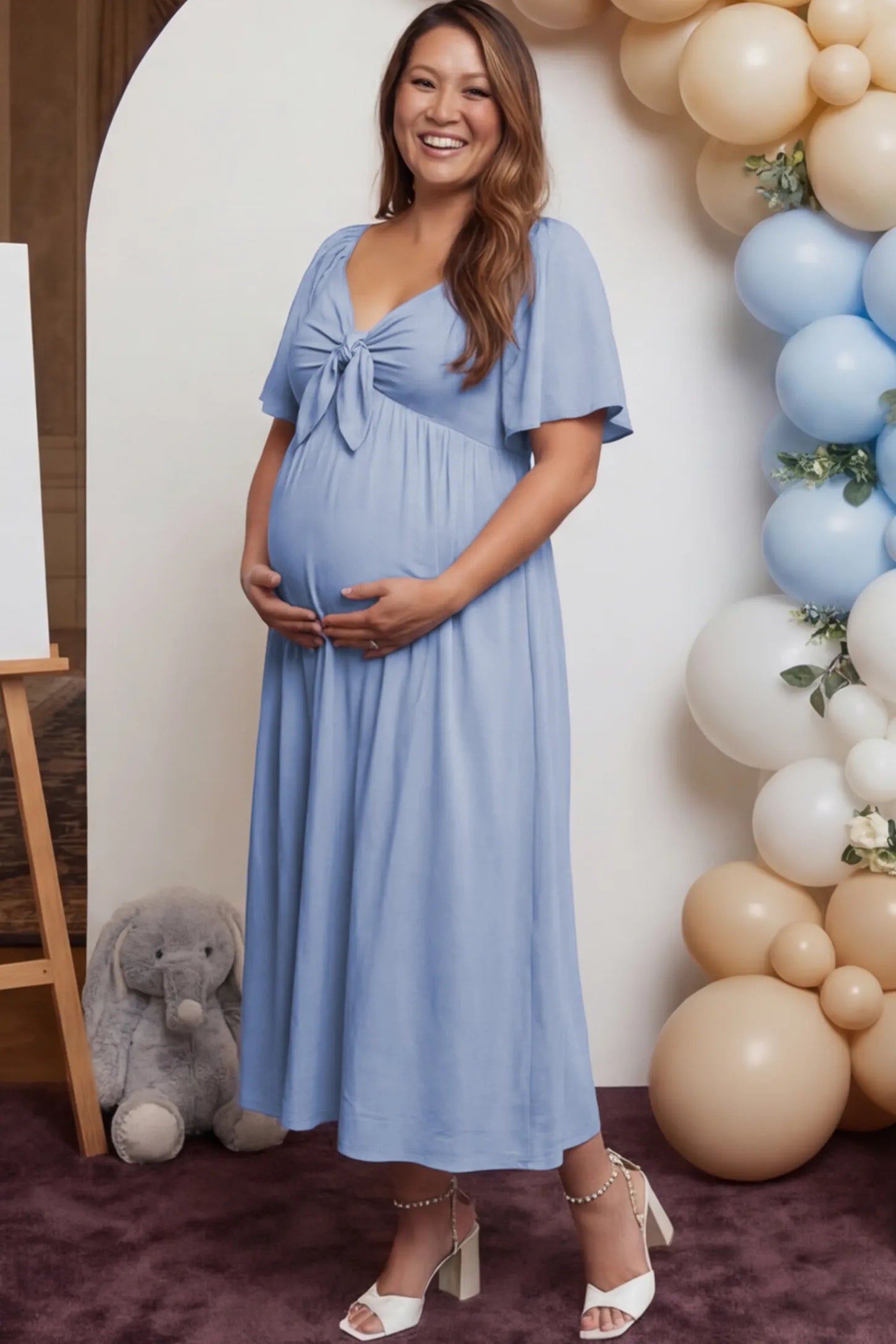 Front Tie Flutter Sleeve Maternity Midi Dress Front Tie Flutter Sleeve Maternity Midi Dress in Light Blue featuring a knotted V-neckline and flowy skirt on a pregnant woman.