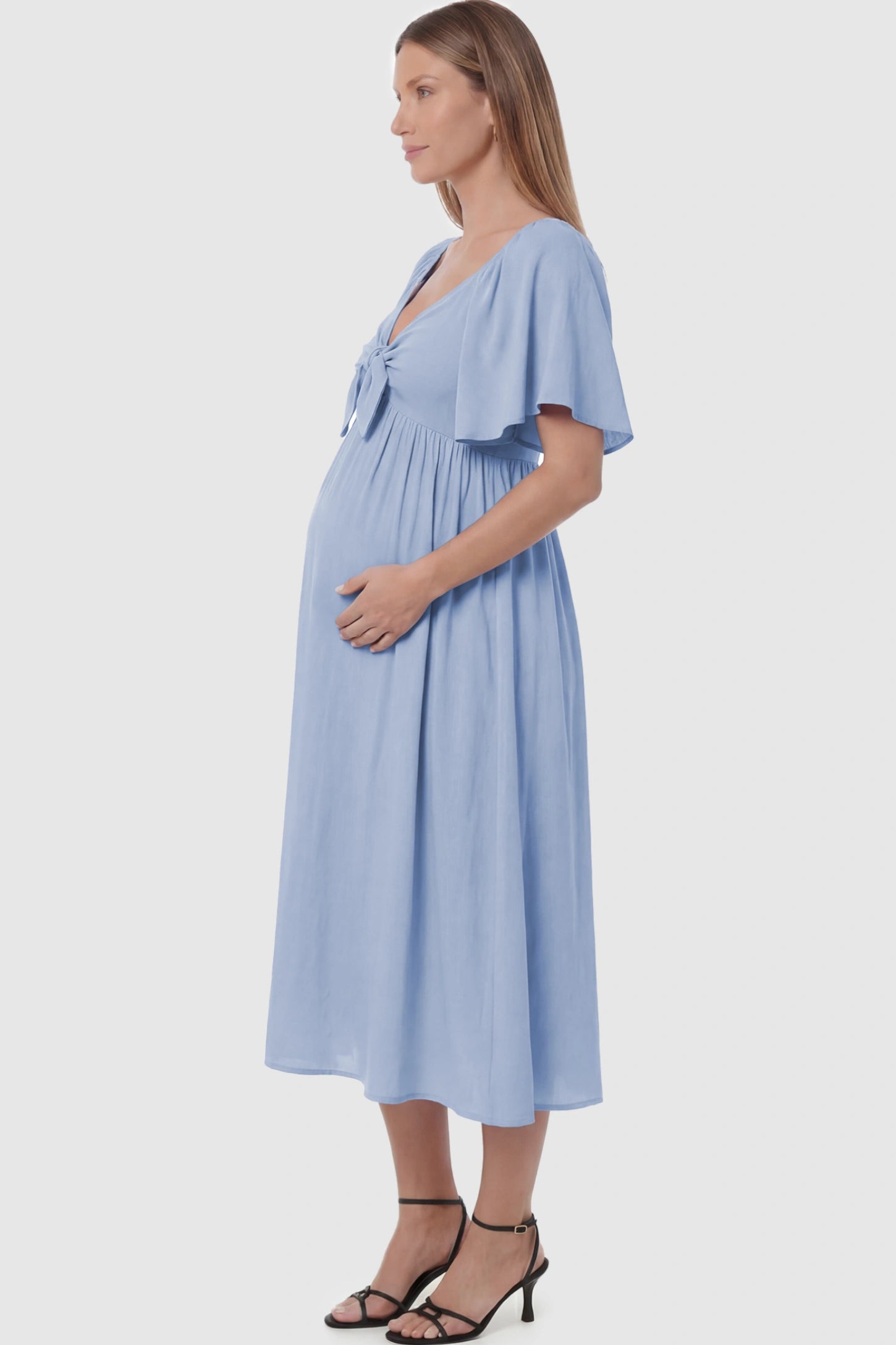 Front Tie Flutter Sleeve Maternity Midi Dress Front Tie Flutter Sleeve Maternity Midi Dress in light blue featuring a knotted V-neckline and flowy skirt on a pregnant model showing side.