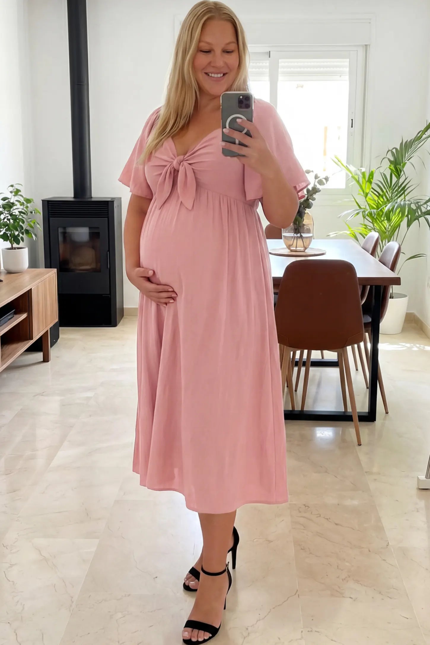 Front Tie Flutter Sleeve Maternity Midi Dress Front Tie Flutter Sleeve Maternity Midi Dress in pink featuring a knotted V-neckline and flowy skirt on a pregnant woman showing front.