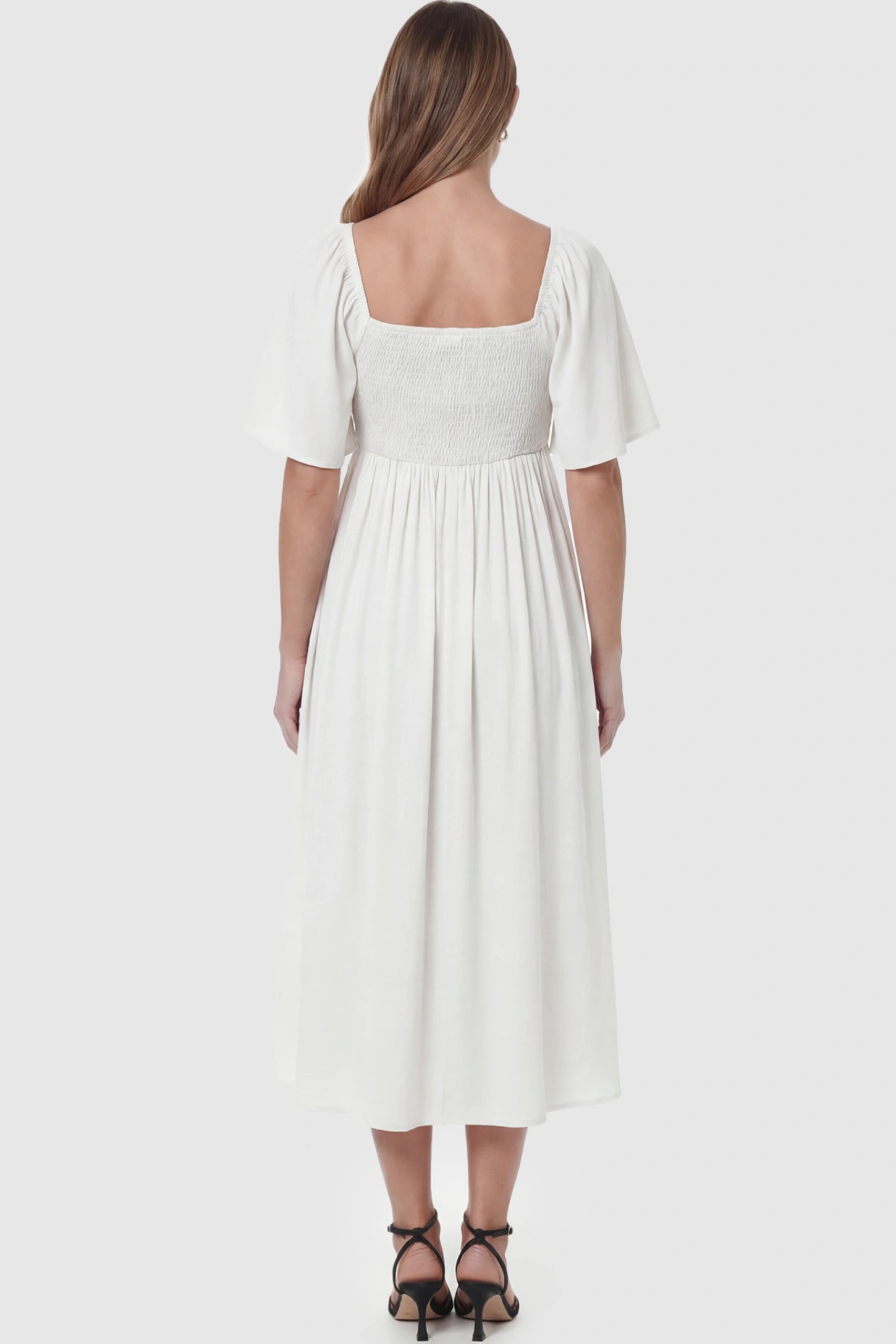 Front Tie Flutter Sleeve Maternity Midi Dress Front Tie Flutter Sleeve Maternity Midi Dress in white featuring a knotted V-neckline and flowy skirt on a pregnant model showing back.