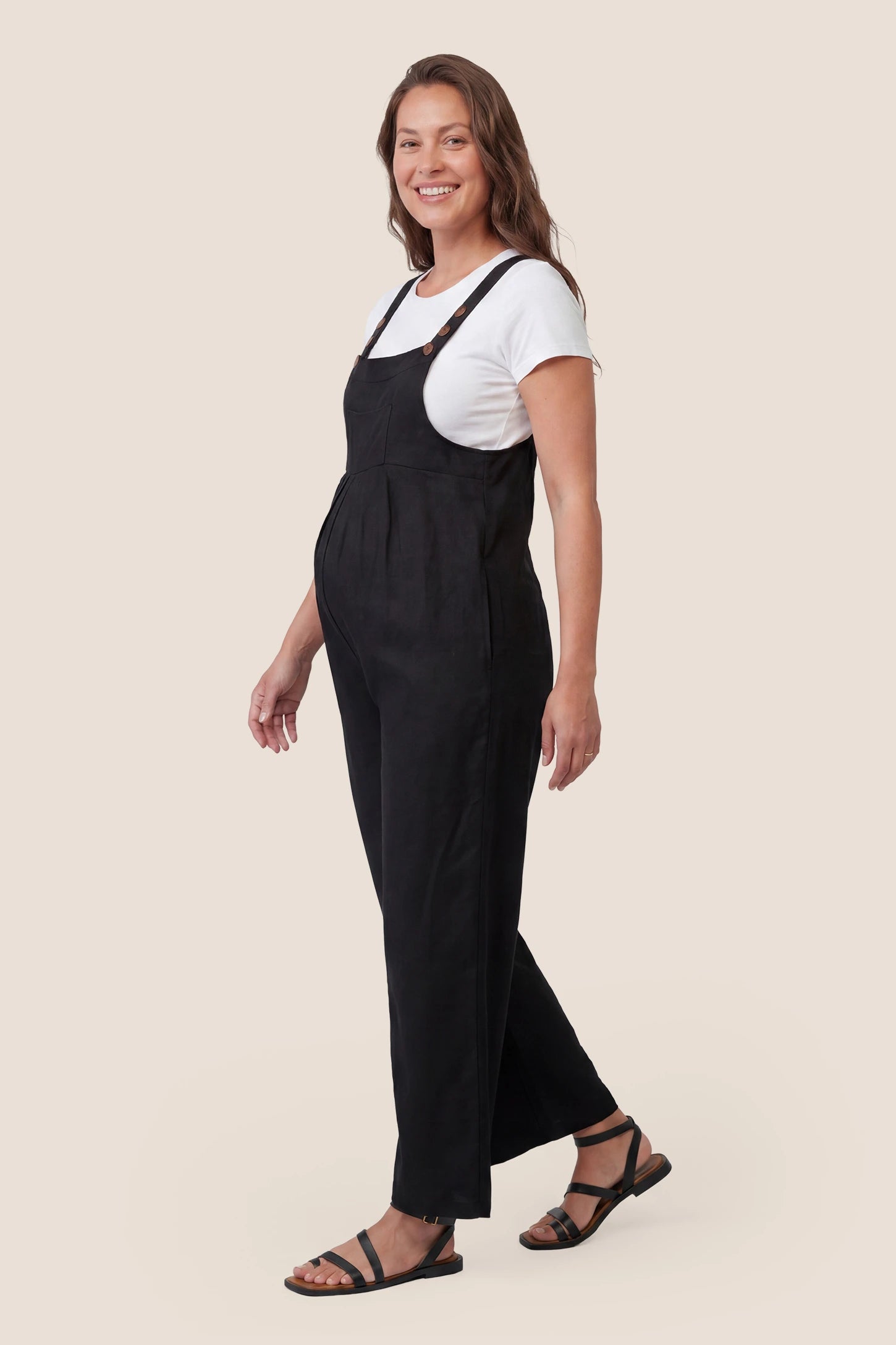 Full-Length Pocketed Maternity Jumpsuit Full-Length Pocketed Maternity Jumpsuit in Black featuring a relaxed wide-leg cut on a pregnant model, side view.
