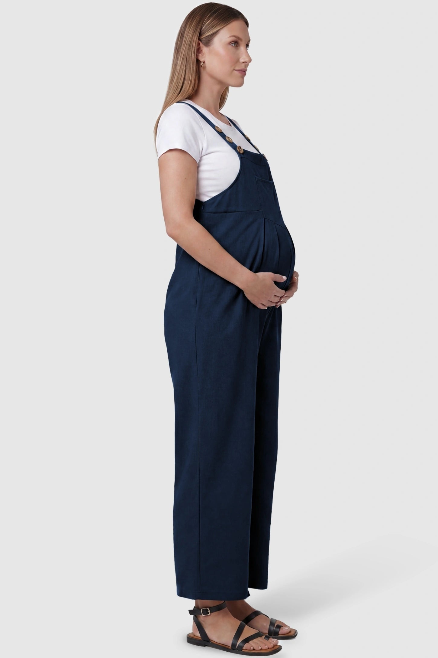Full-Length Pocketed Maternity Jumpsuit Full-Length Pocketed Maternity Jumpsuit in Dark Blue featuring a relaxed wide-leg cut on a pregnant model, side view.