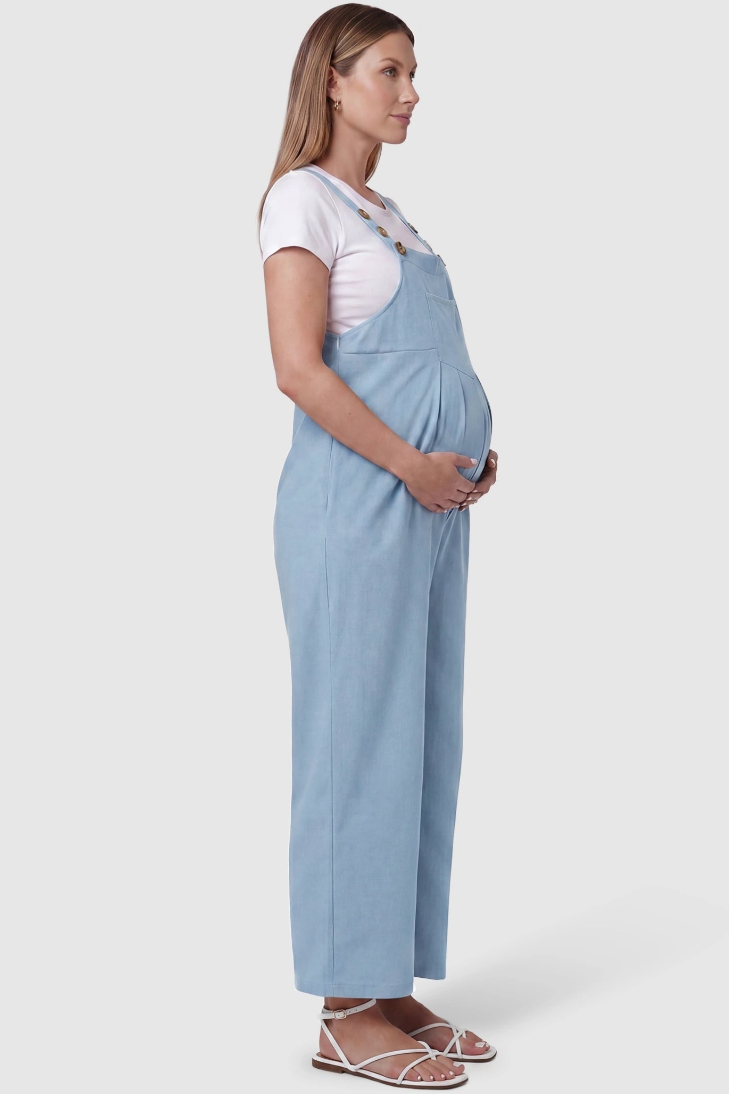 Full-Length Pocketed Maternity Jumpsuit Full-Length Pocketed Maternity Jumpsuit in Light Blue featuring a relaxed wide-leg cut on a pregnant model, side view.