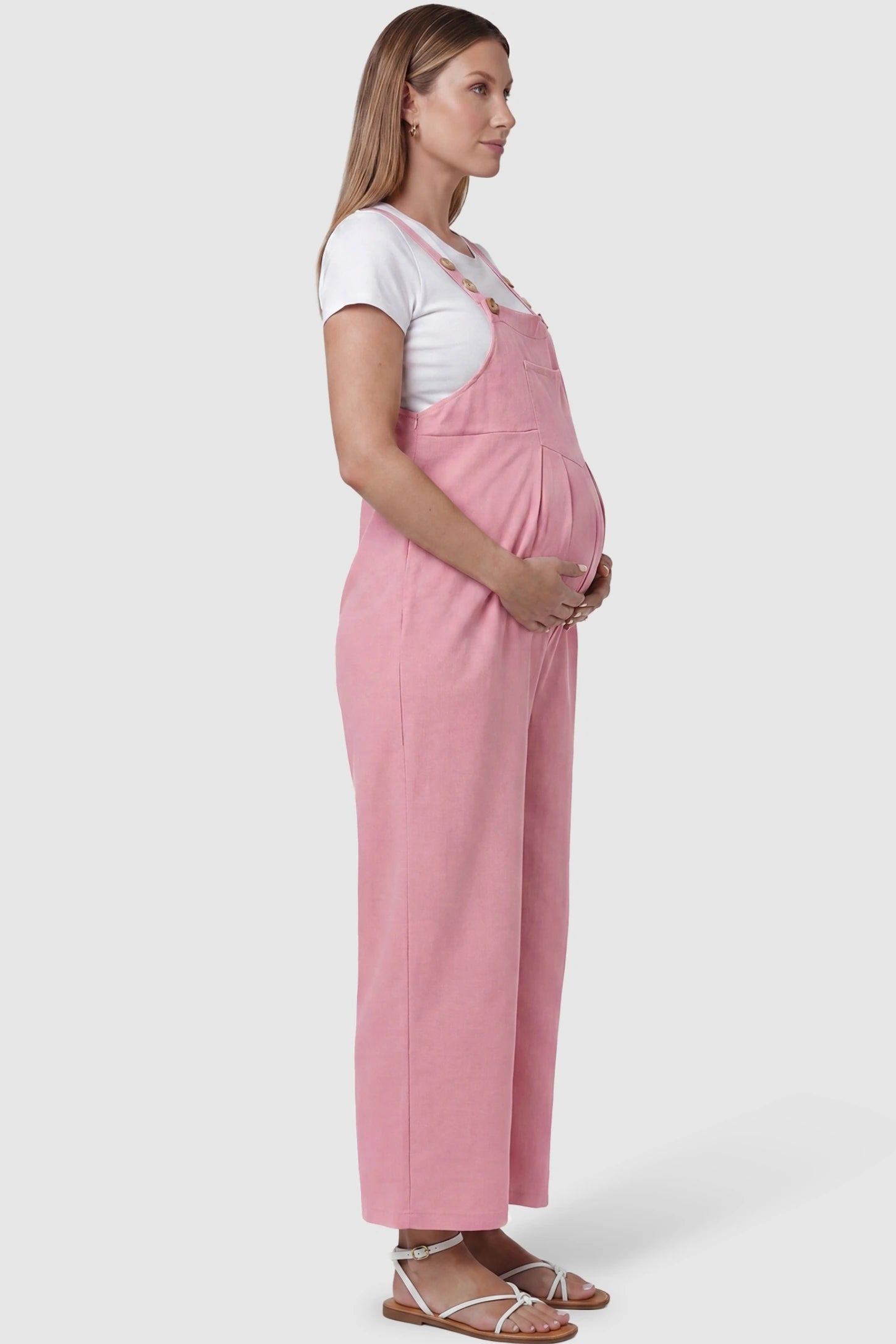 Full-Length Pocketed Maternity Jumpsuit Full-Length Pocketed Maternity Jumpsuit in Pink featuring a relaxed wide-leg cut on a pregnant model, side view.