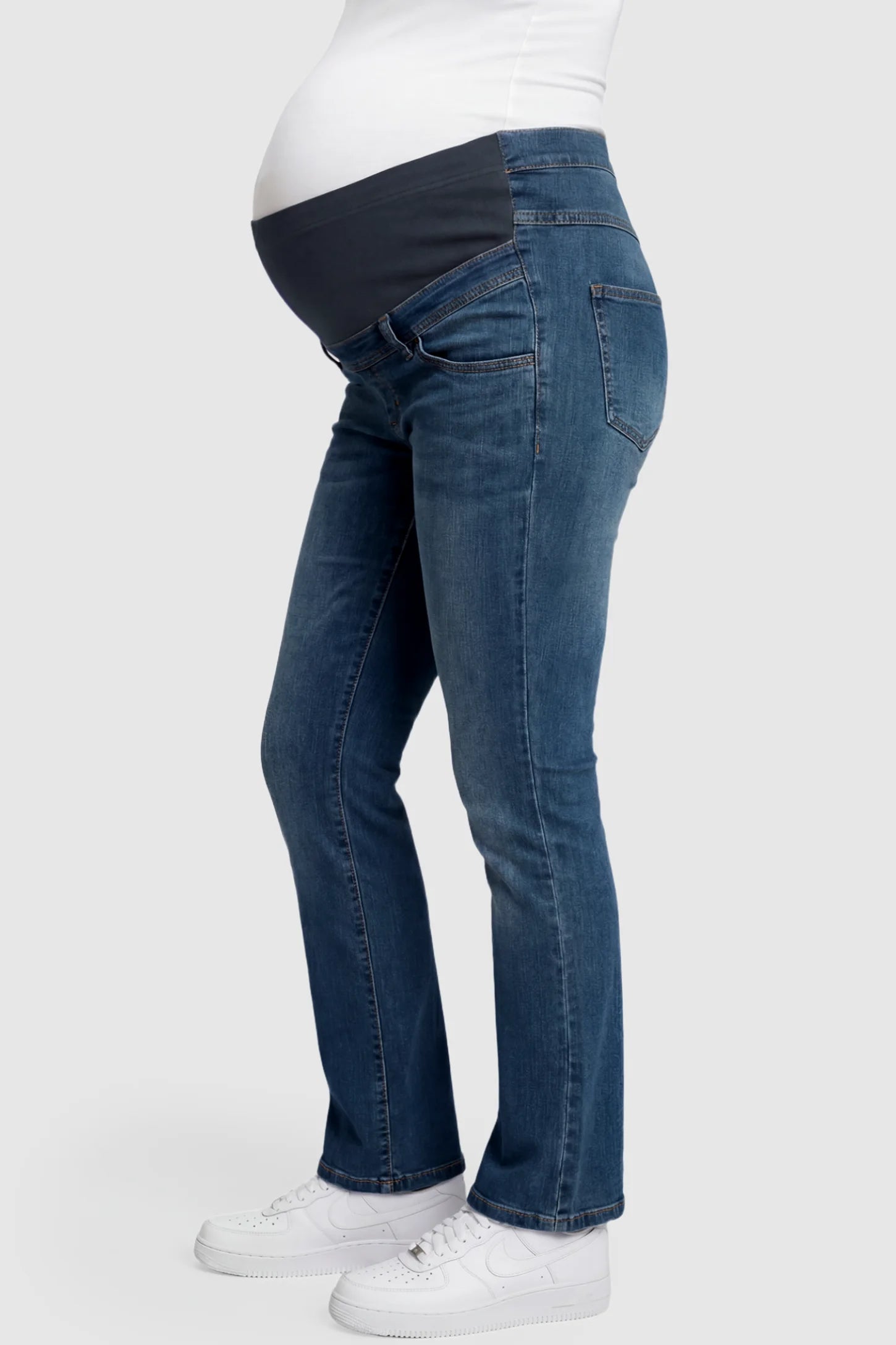 Full Panel Bootcut Maternity Jeans Full Panel Bootcut Maternity Jeans in medium wash blue featuring a stretchy over-the-belly panel on a pregnant model showing side.