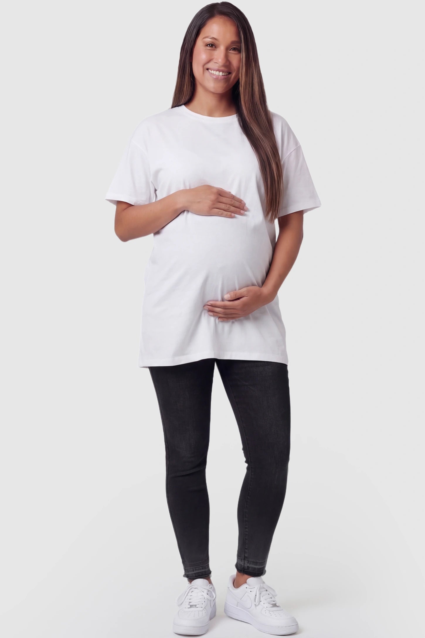 Full Panel Released Hem Maternity Skinny Jeans Full Panel Released Hem Maternity Skinny Jeans in Black featuring a released hem and over-the-belly panel on a pregnant model facing front.
