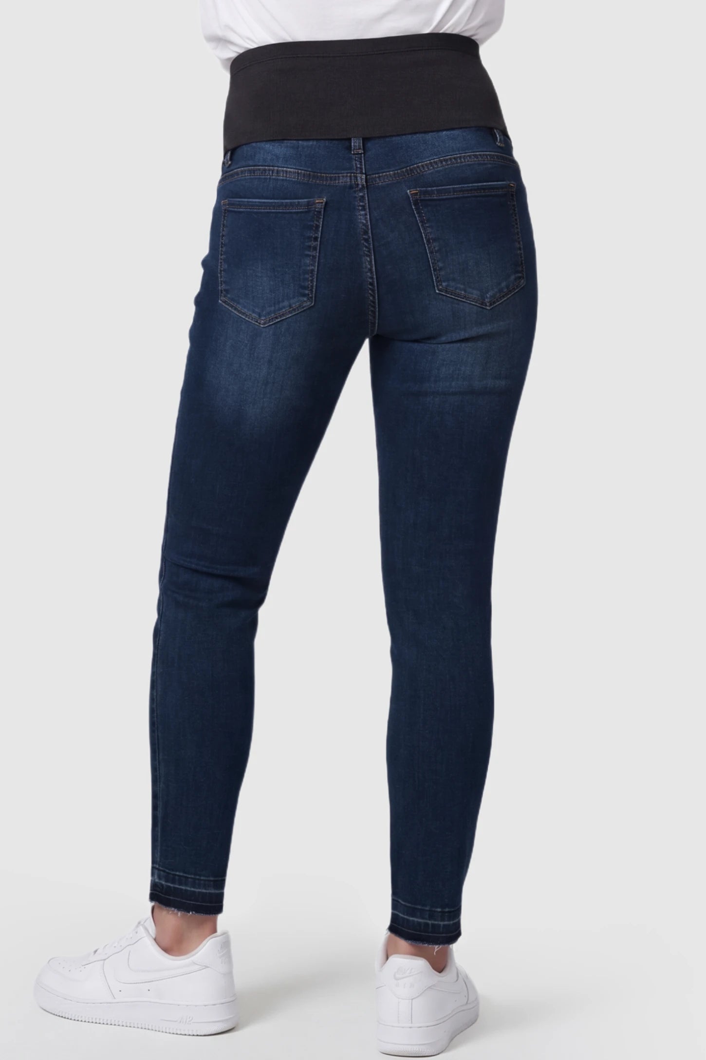 Full Panel Released Hem Maternity Skinny Jeans Full Panel Released Hem Maternity Skinny Jeans in Dark Blue featuring a released hem on a pregnant model showing back.