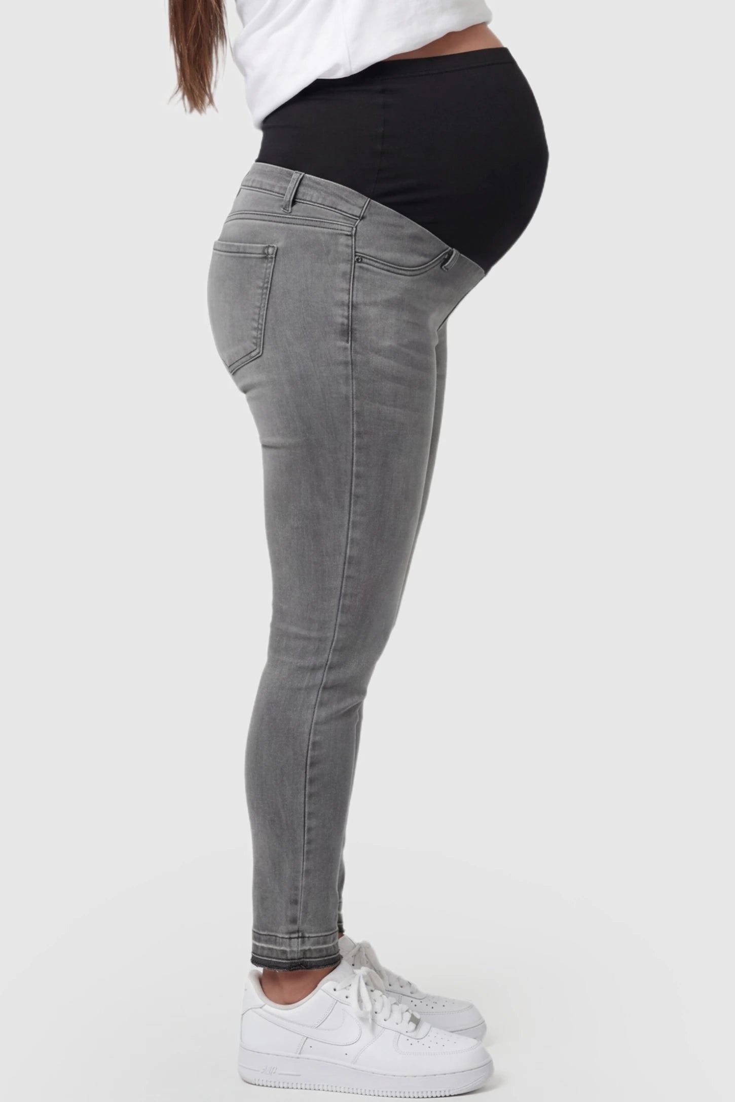 Full Panel Released Hem Maternity Skinny Jeans Full Panel Released Hem Maternity Skinny Jeans in Gray featuring a released hem and over-the-belly panel on a pregnant model showing side.