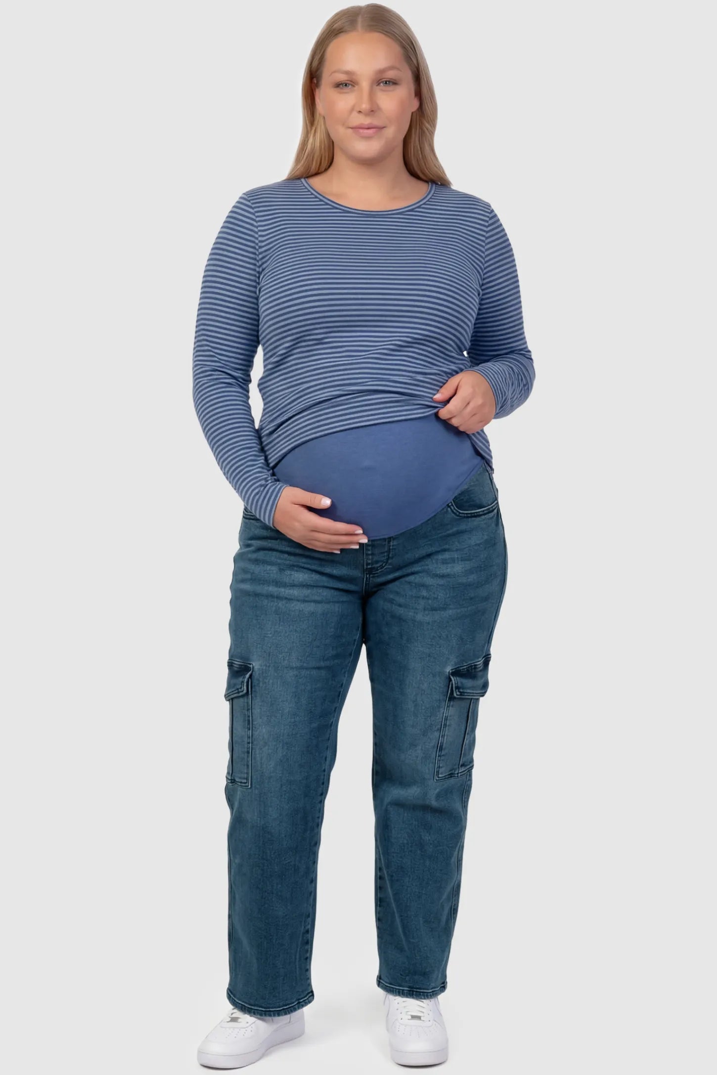 Full Panel Wide Leg Maternity Cargo Jeans Full Panel Wide Leg Maternity Cargo Jeans in Denim Blue featuring functional side flap pockets on a plus size pregnant model front view.