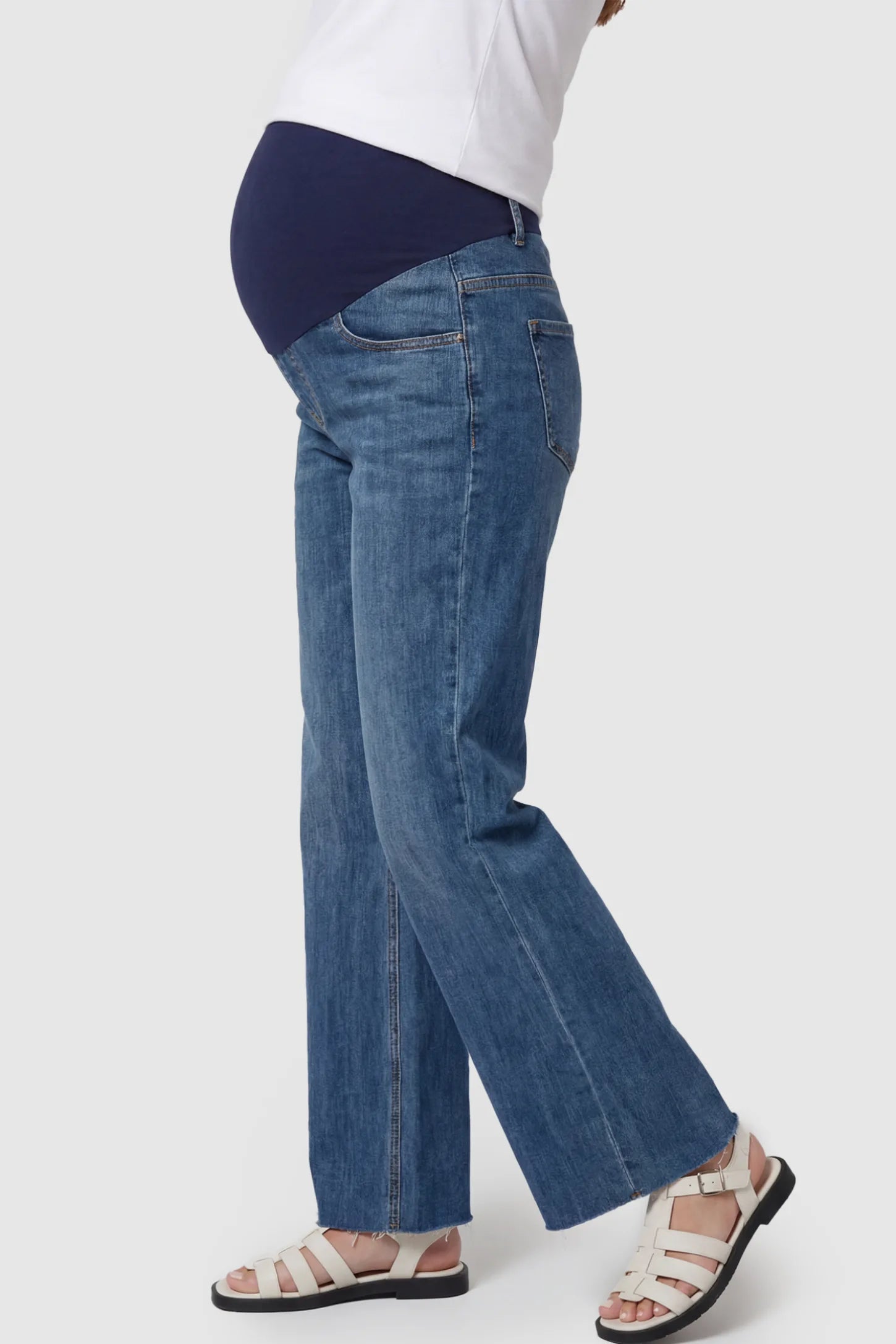 Full Panel Wide Leg Maternity Jeans Full Panel Wide Leg Maternity Jeans in Dark Blue featuring a seamless tummy-support band on a pregnant model showing side.