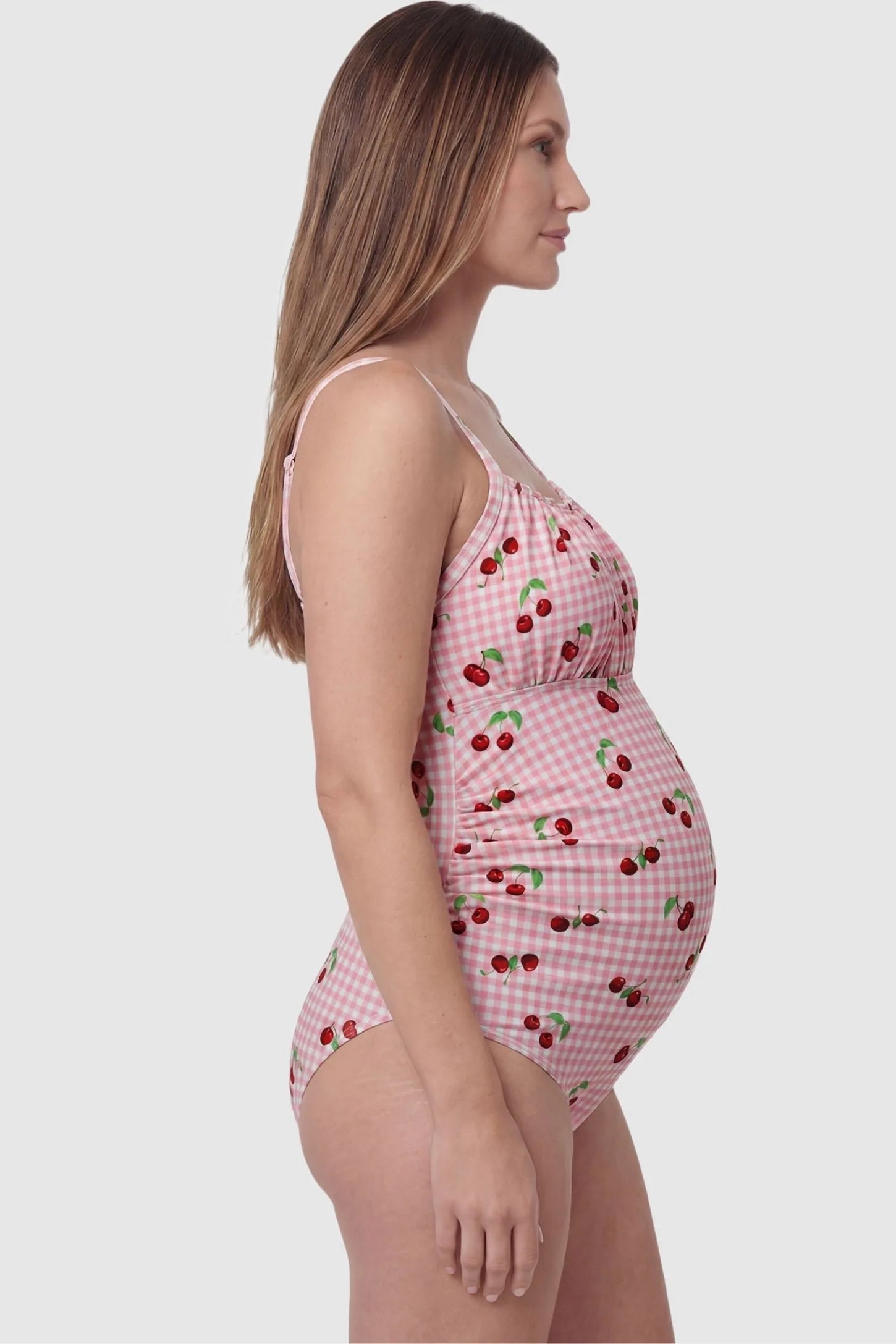 Gingham Matte Ruched Fit Maternity Swimsuit Gingham Matte Ruched Fit Maternity Swimsuit in pink with side ruching for belly support, side view on pregnant model.