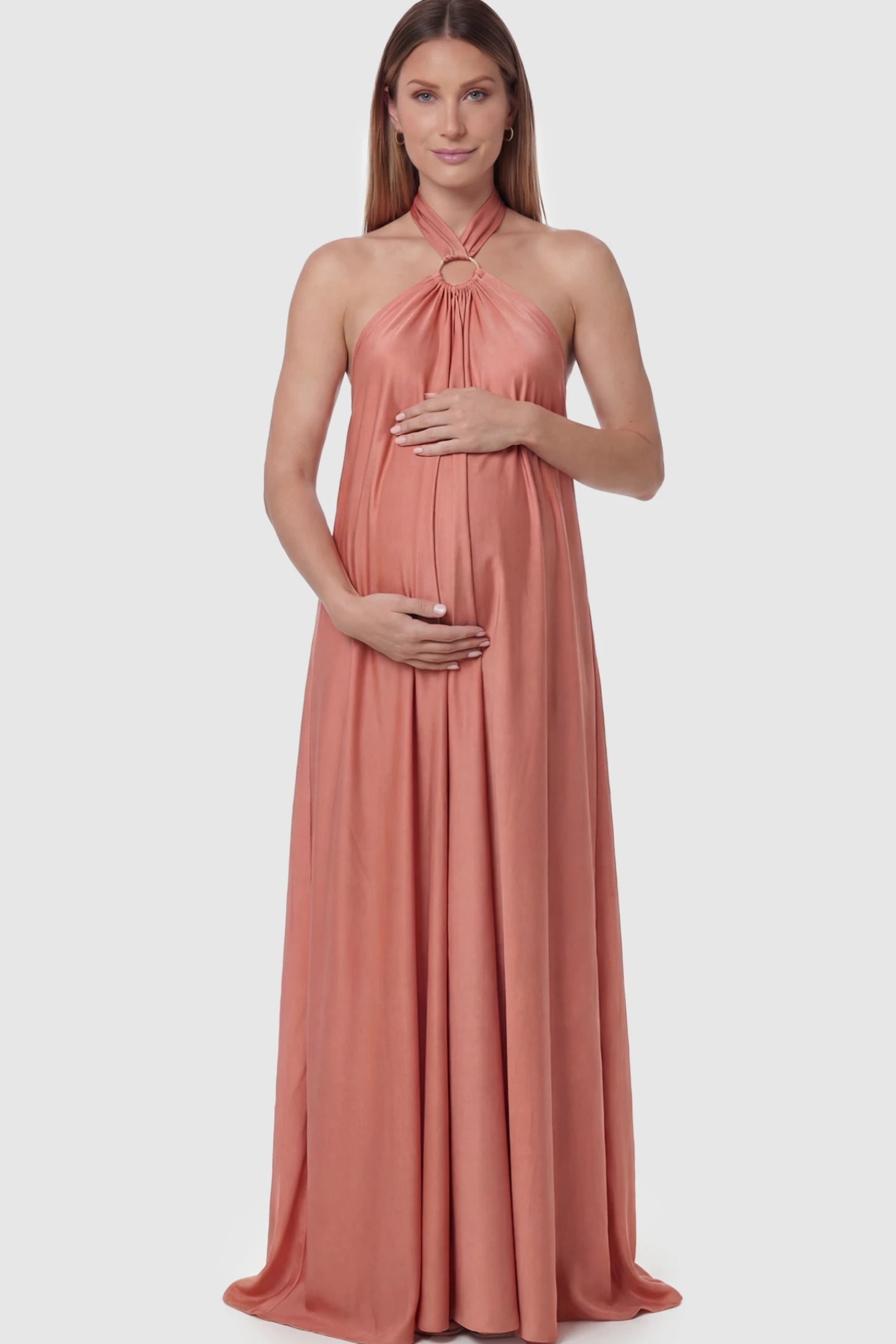 Solid Halter Neck Maternity Maxi Dress Solid Halter Neck Maternity Maxi Dress in Pink featuring a flowing skirt on a pregnant model posing front.