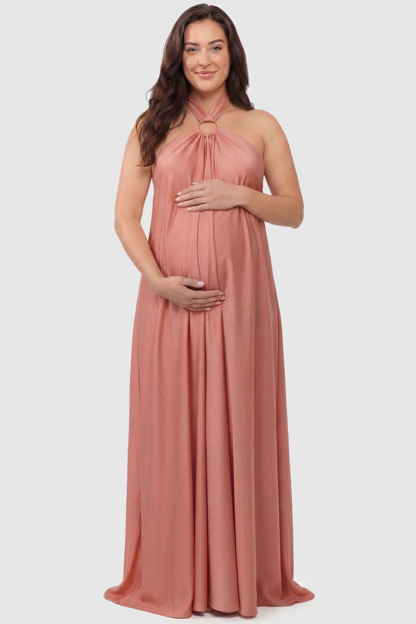 Solid Halter Neck Maternity Maxi Dress Solid Halter Neck Maternity Maxi Dress in Pink featuring a flowing skirt on a plus size pregnant model, front view.
