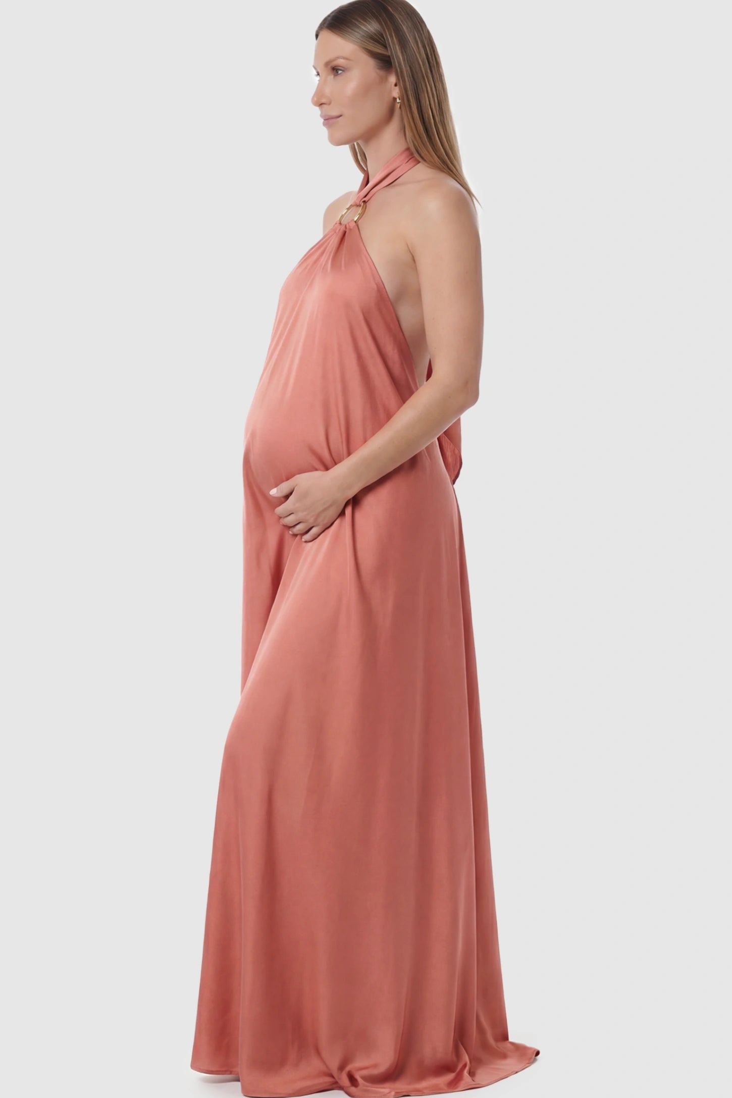 Solid Halter Neck Maternity Maxi Dress Solid Halter Neck Maternity Maxi Dress in Pink featuring a flowing skirt on a pregnant model showing side.