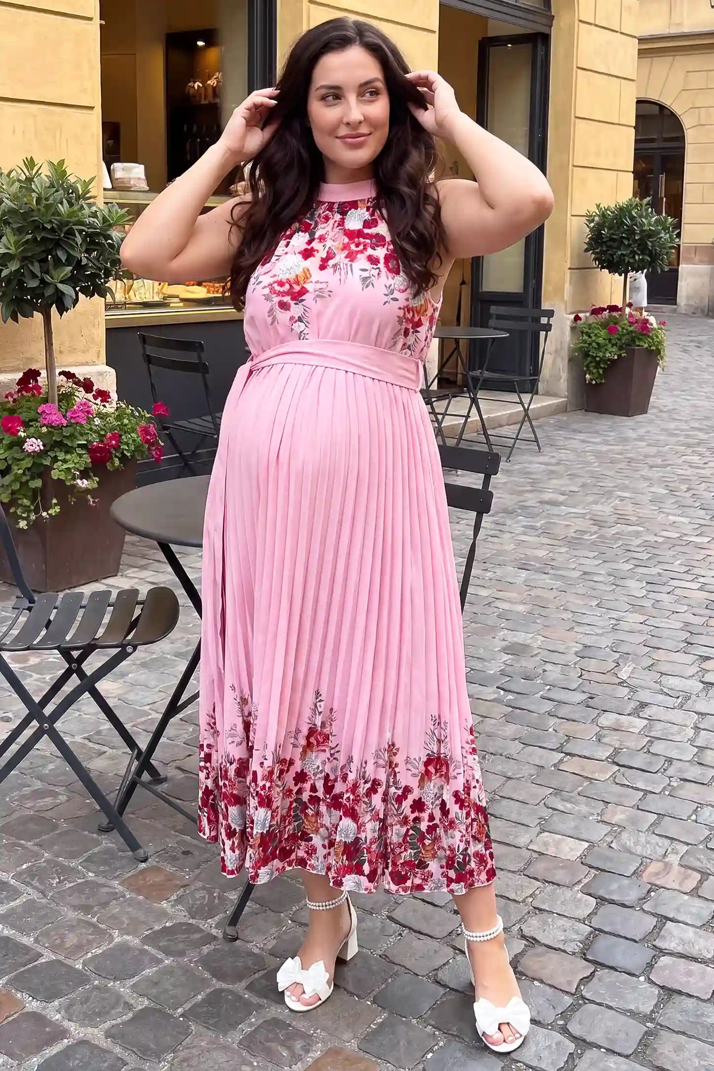 Halter Neck Pleated Maternity Midi Dress Halter Neck Pleated Maternity Midi Dress in Rose Pink Floral featuring a flattering A-line fit, lifestyle view on a plus-size model.