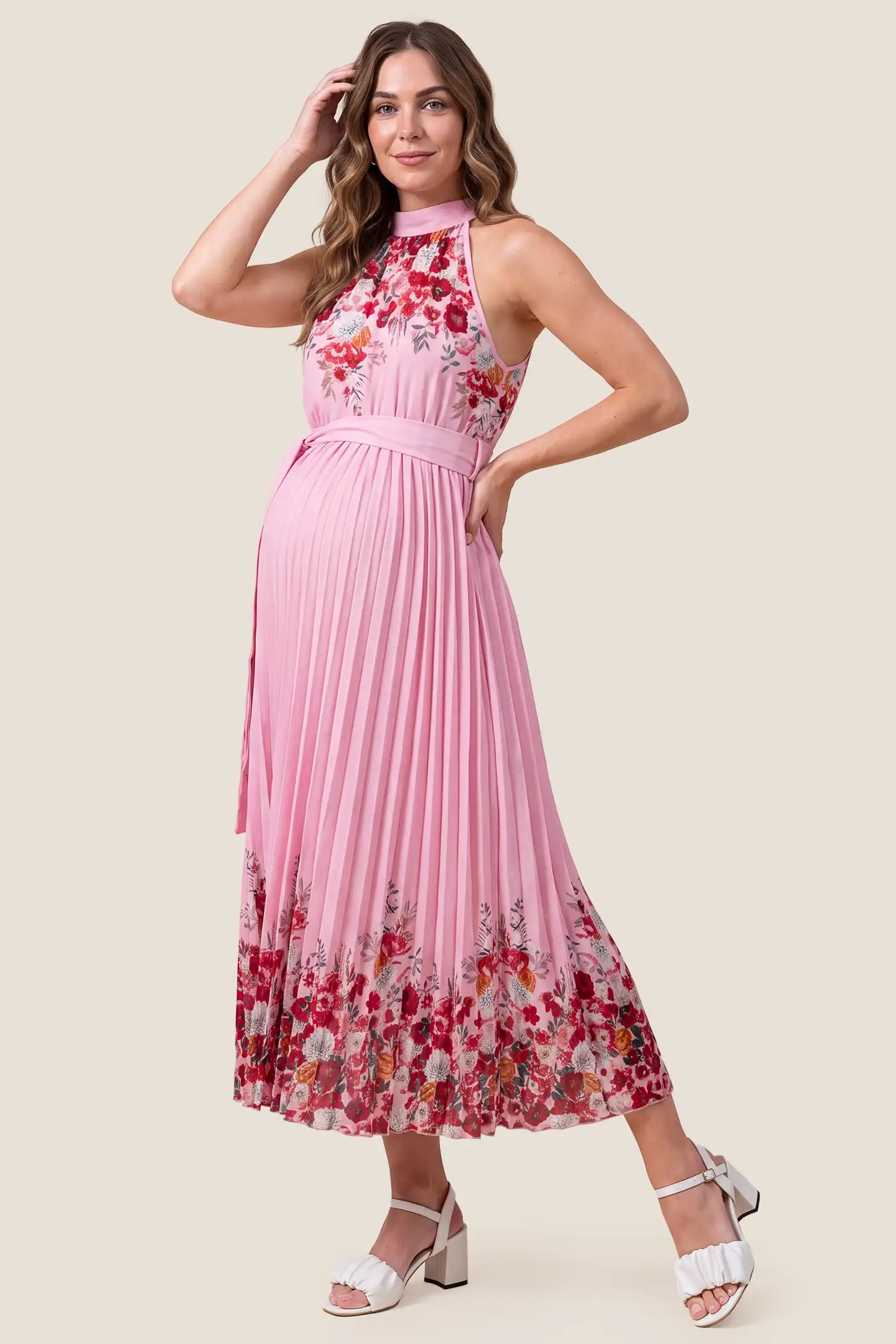 Halter Neck Pleated Maternity Midi Dress Halter Neck Pleated Maternity Midi Dress in Rose Pink Floral accommodating a growing bump on a pregnant model, studio side view.