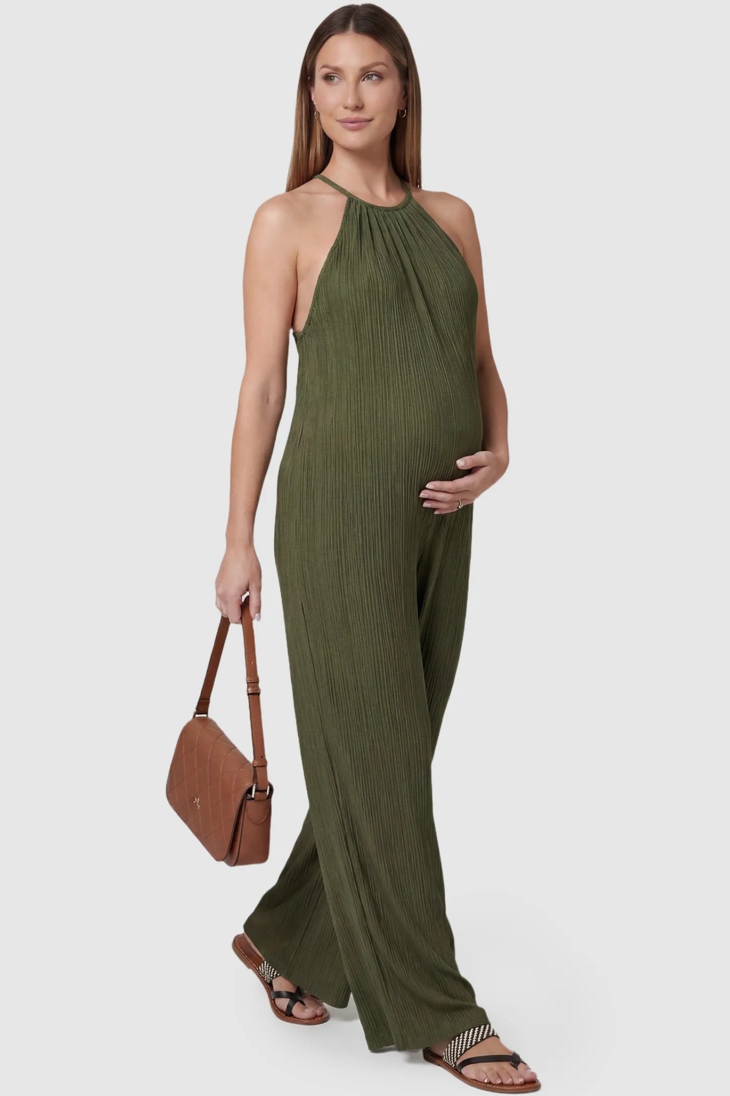 Halter Neck Wide Leg Pocketed Maternity Jumpsuit Halter Neck Wide Leg Pocketed Maternity Jumpsuit in Army Green featuring a gathered halter neck and ribbed texture on a pregnant model, styled lifestyle view.