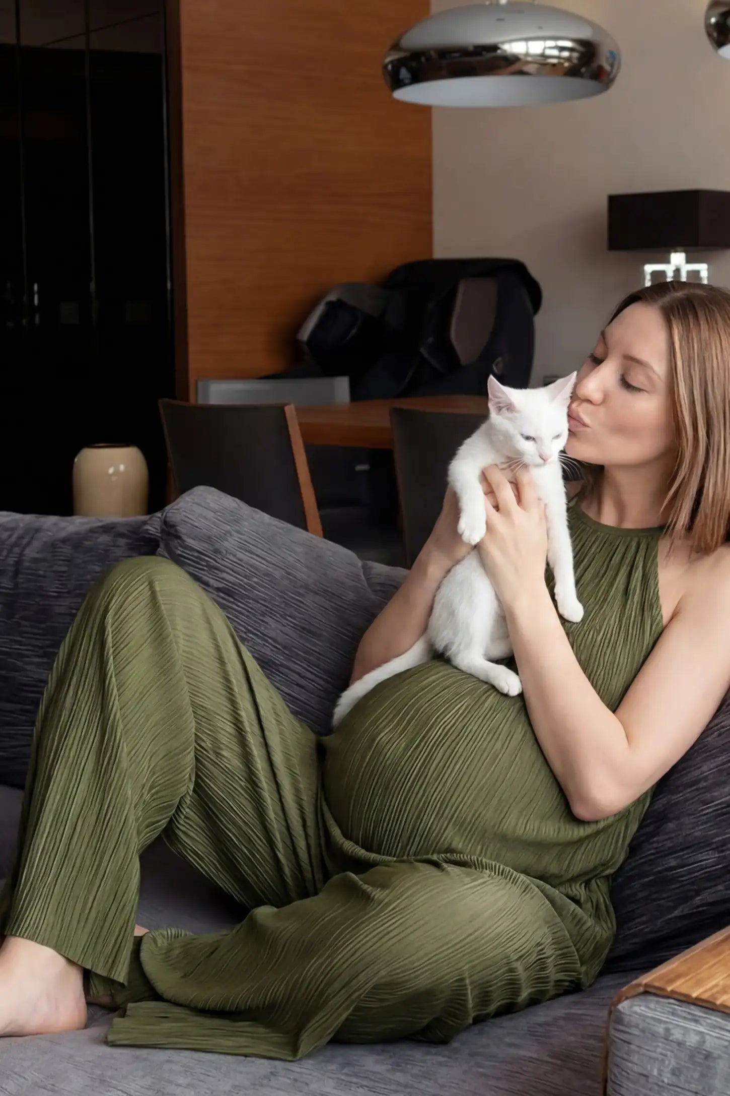 Halter Neck Wide Leg Pocketed Maternity Jumpsuit Halter Neck Wide Leg Pocketed Maternity Jumpsuit in Army Green featuring a gathered halter neck and ribbed fabric on a pregnant model, UGC-style view.
