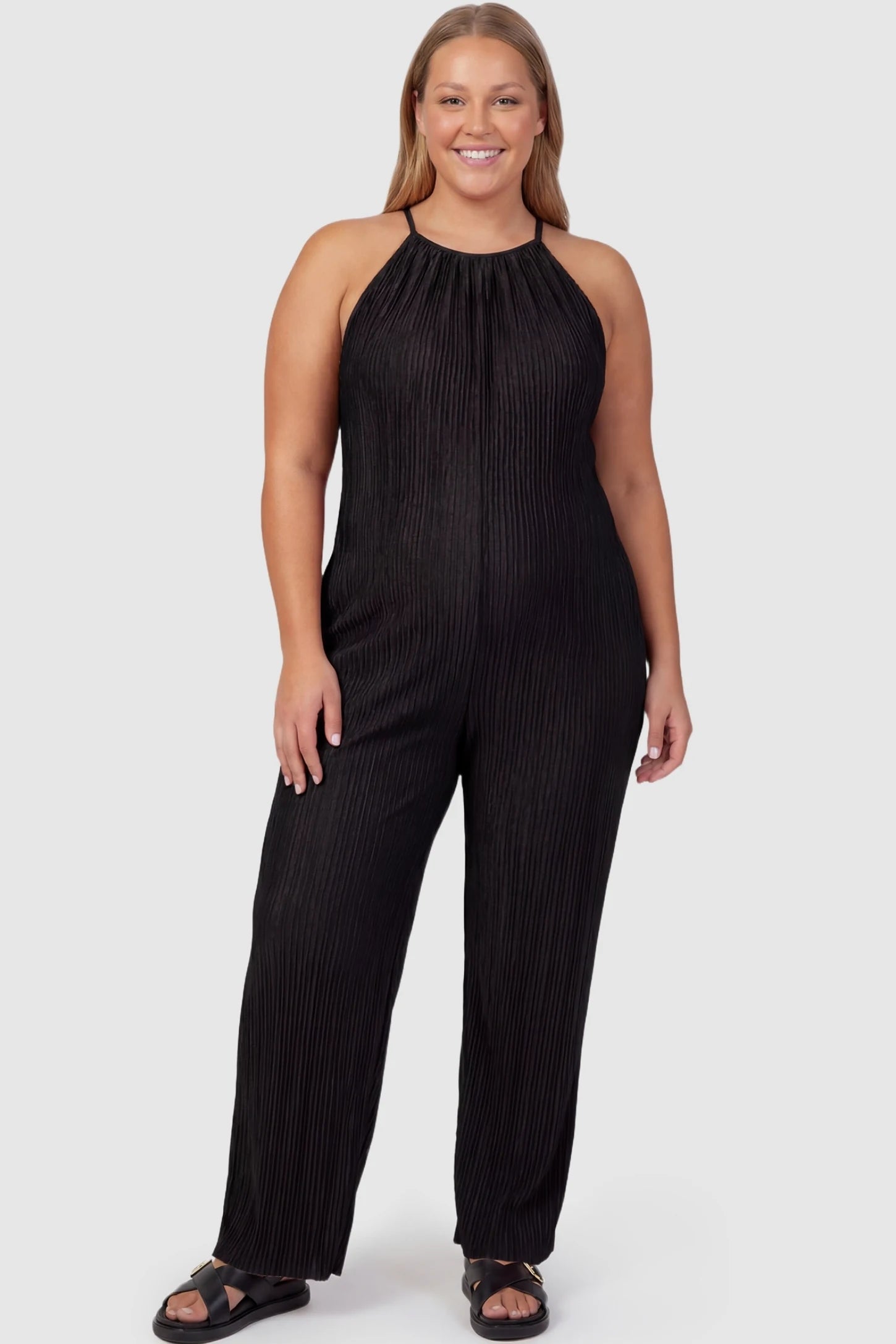 Halter Neck Wide Leg Pocketed Maternity Jumpsuit Halter Neck Wide Leg Pocketed Maternity Jumpsuit in Black featuring a gathered halter neck and ribbed texture on a plus-size pregnant model, front view.
